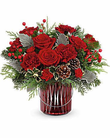 Red roses arranged in a red glass vase with pinecones and berries