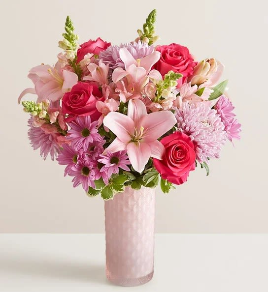 Pink and lavender bouquet with roses and lilies in a tall pink vase