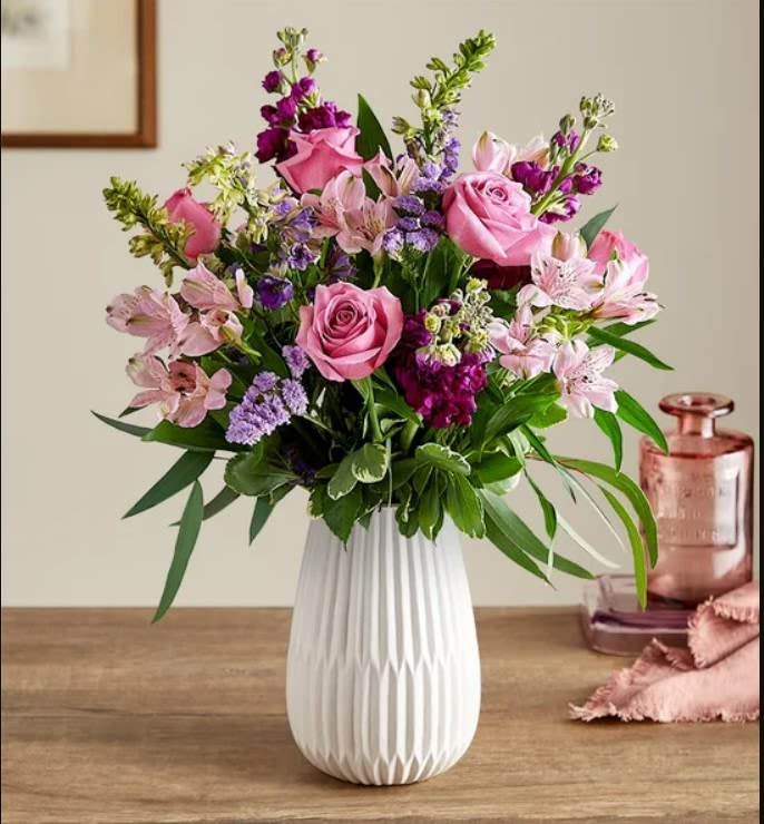 Pink roses and purple flowers in a white vase