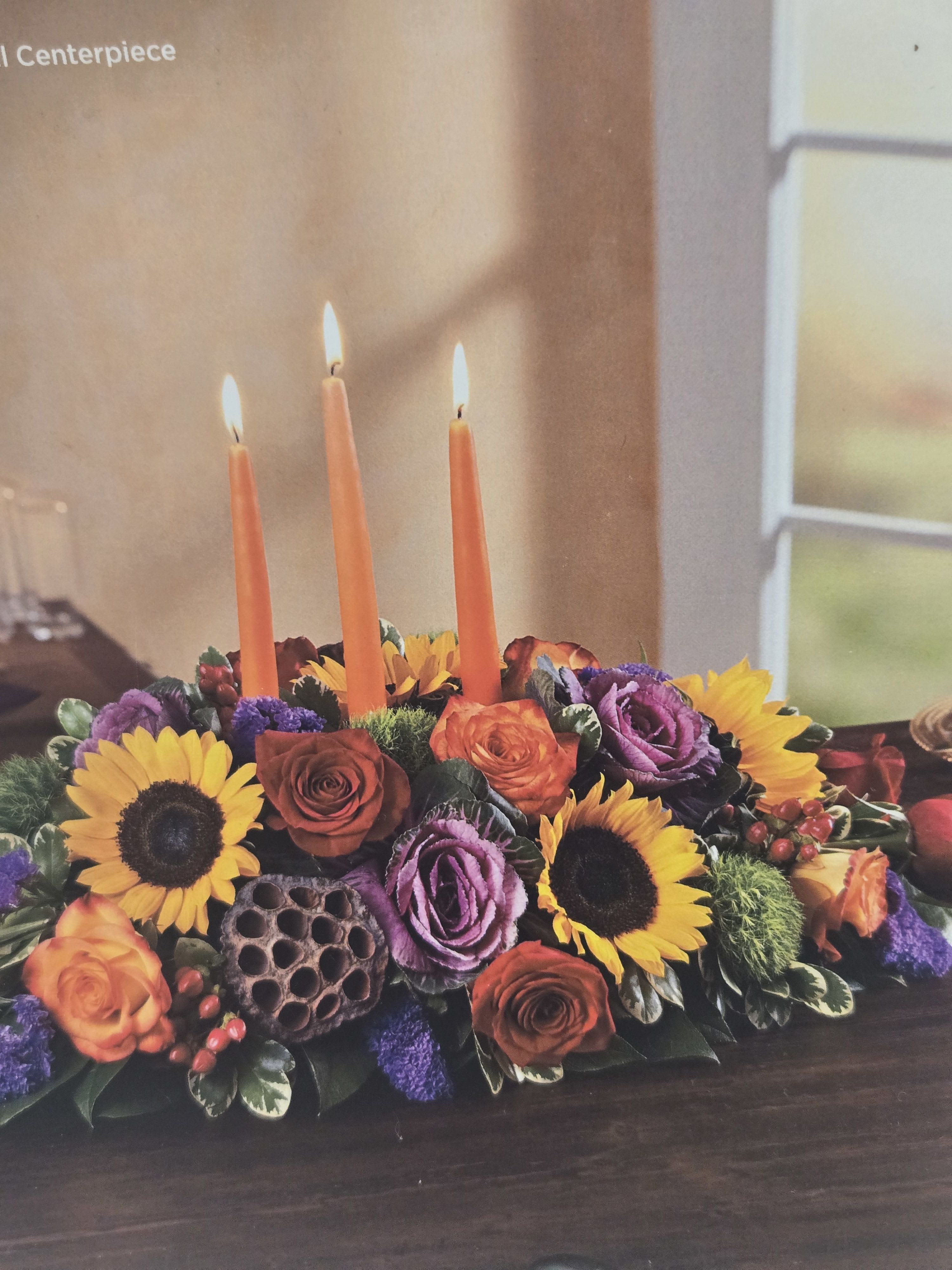 Floral centerpiece with orange candles and sunflowers