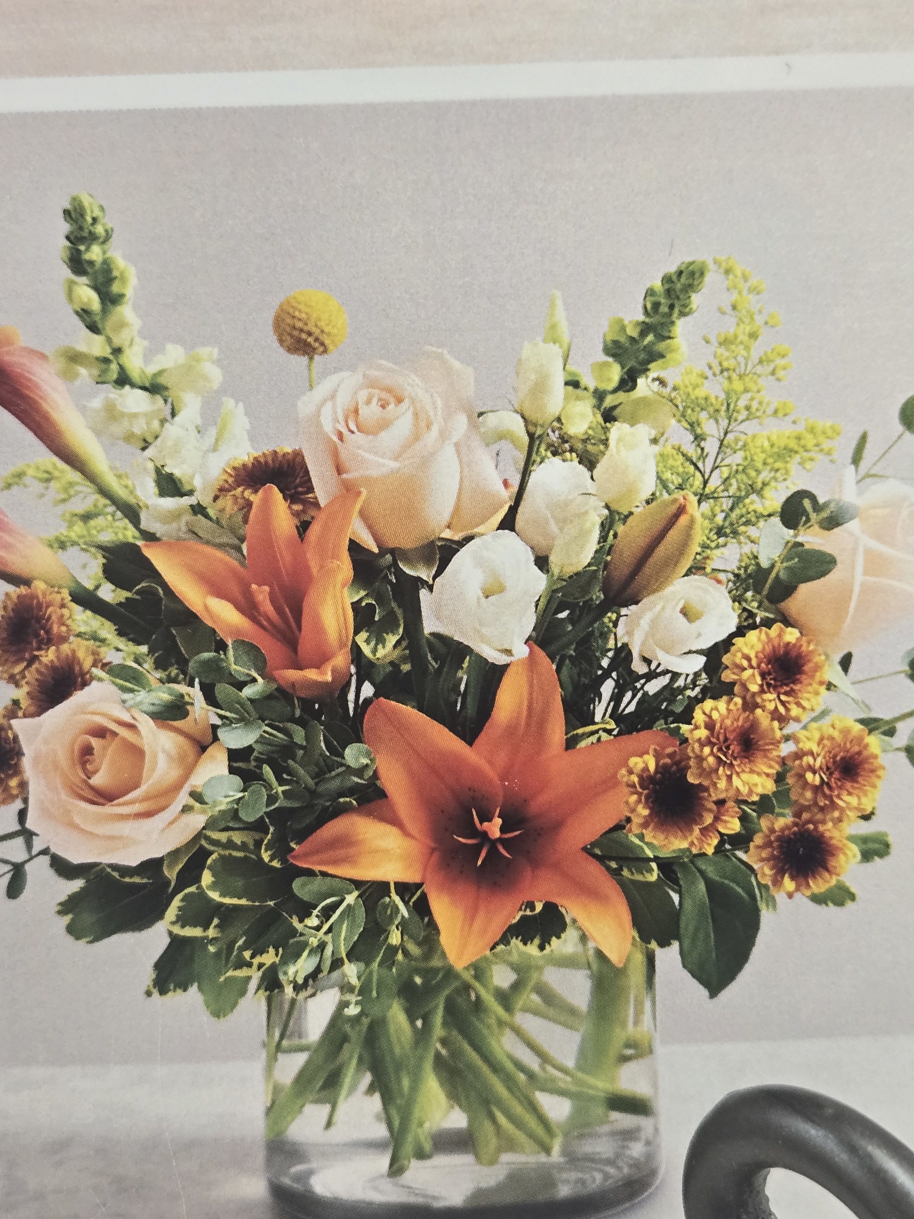 Bouquet of orange lilies, peach roses, and white blooms in a glass vase