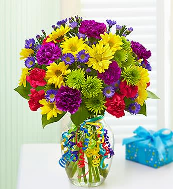 It's Your Day Bouquet - Product ID: 91333  Birthdays. Congratulations. A quick pick-me-up. Celebrate any occasion with our bright bouquet of fresh carnations, daisy poms and more, and let them know they deserve a day that's all about them! Hand-designed bouquet of carnations, mini carnations, daisy poms, poms, monte casino and salal, beautifully hand-designed by our select florists Please note each stem contains multiple blooms so bloom count may vary Gathered in a stylish glass vase tied with colorful ribbon; vase measures 8"H x 4"D Large arrangement measures approximately 13"H x 7"W Medium arrangement measures approximately 12"H x 6"W Small arrangement measures approximately 11"H x 5"W Our florists hand-design each arrangement, so colors, varieties, and container may vary due to local availability