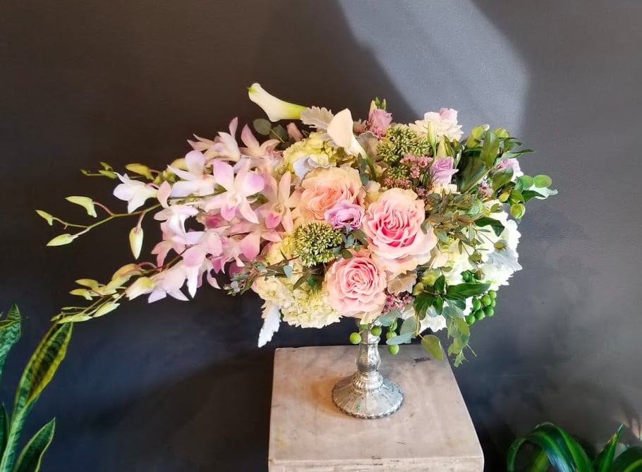 Pink roses and pale orchids arranged in a silver vase