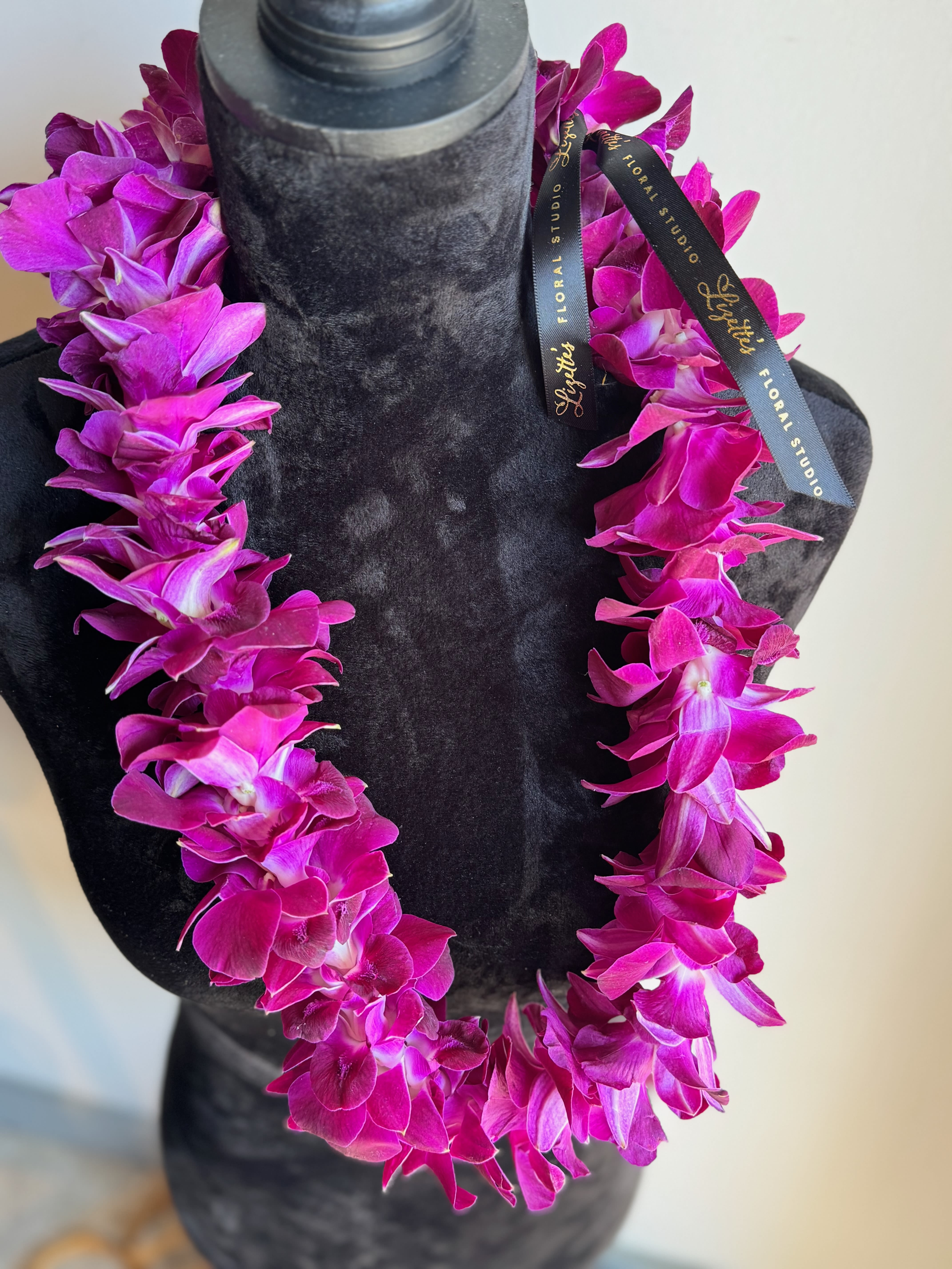 Orchid Lei - Our stunning Dendrobium Orchid Leis are the perfect accessory for any special occasion, including Father's Day, graduations, parties, and weddings. Suitable for both men and women, these leis feature approximately 40-45 handpicked Dendrobium Orchid blooms, carefully strung together to create a beautiful, elegant piece. Made with the highest quality orchids, this single-strand lei is sure to add a touch of luxury to any celebration.  Care Instructions: To keep your blooms fresh, store your orchid lei in a cool area or refrigerate (42-55ᵒF) until use. With proper care, the blossoms will last 3-7 days. Do not freeze.  Ordering Information: Please place your order at least two weeks in advance to ensure availability. Specify your color preference: white/green or purple orchids.  Product ID: Orchid-lei
