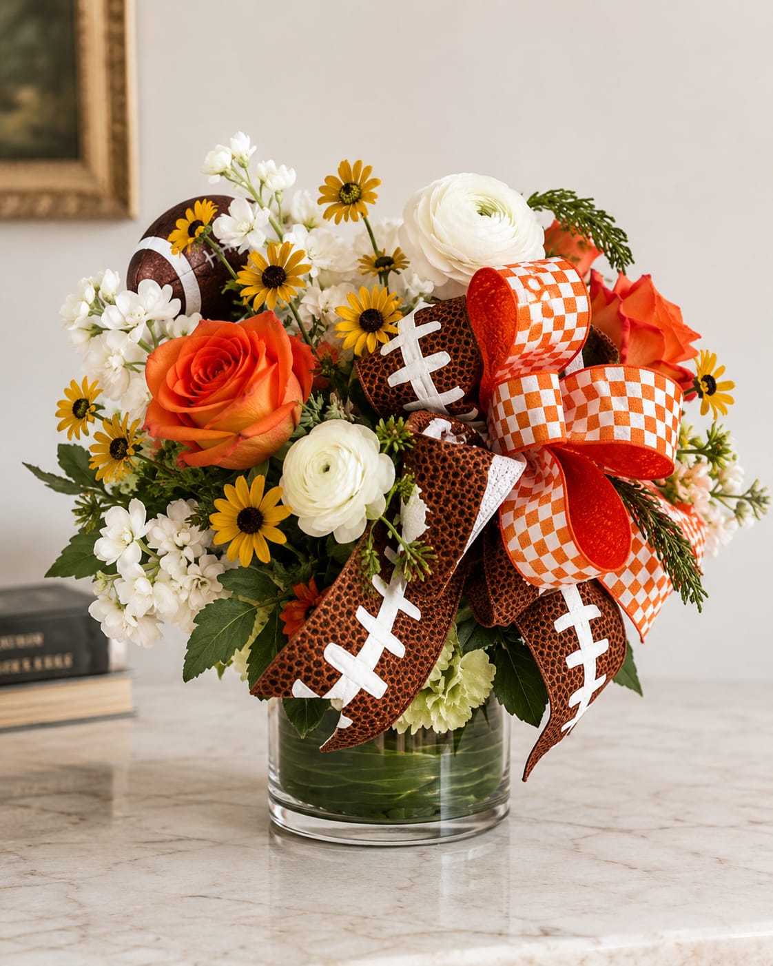 Bouquet of orange and white flowers in a glass vase with football ribbons