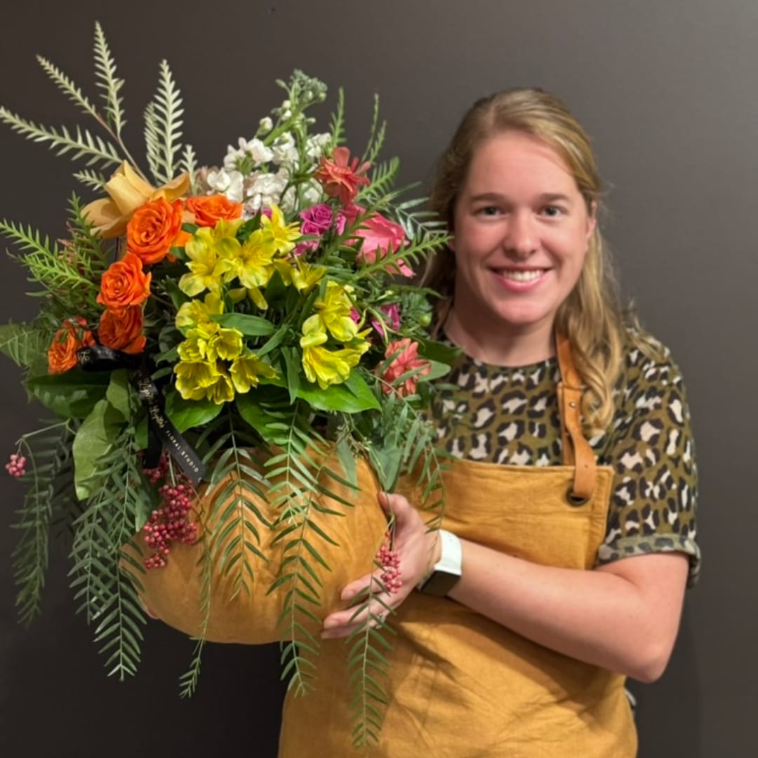 Woman holding a large mixed bouquet in a tan container