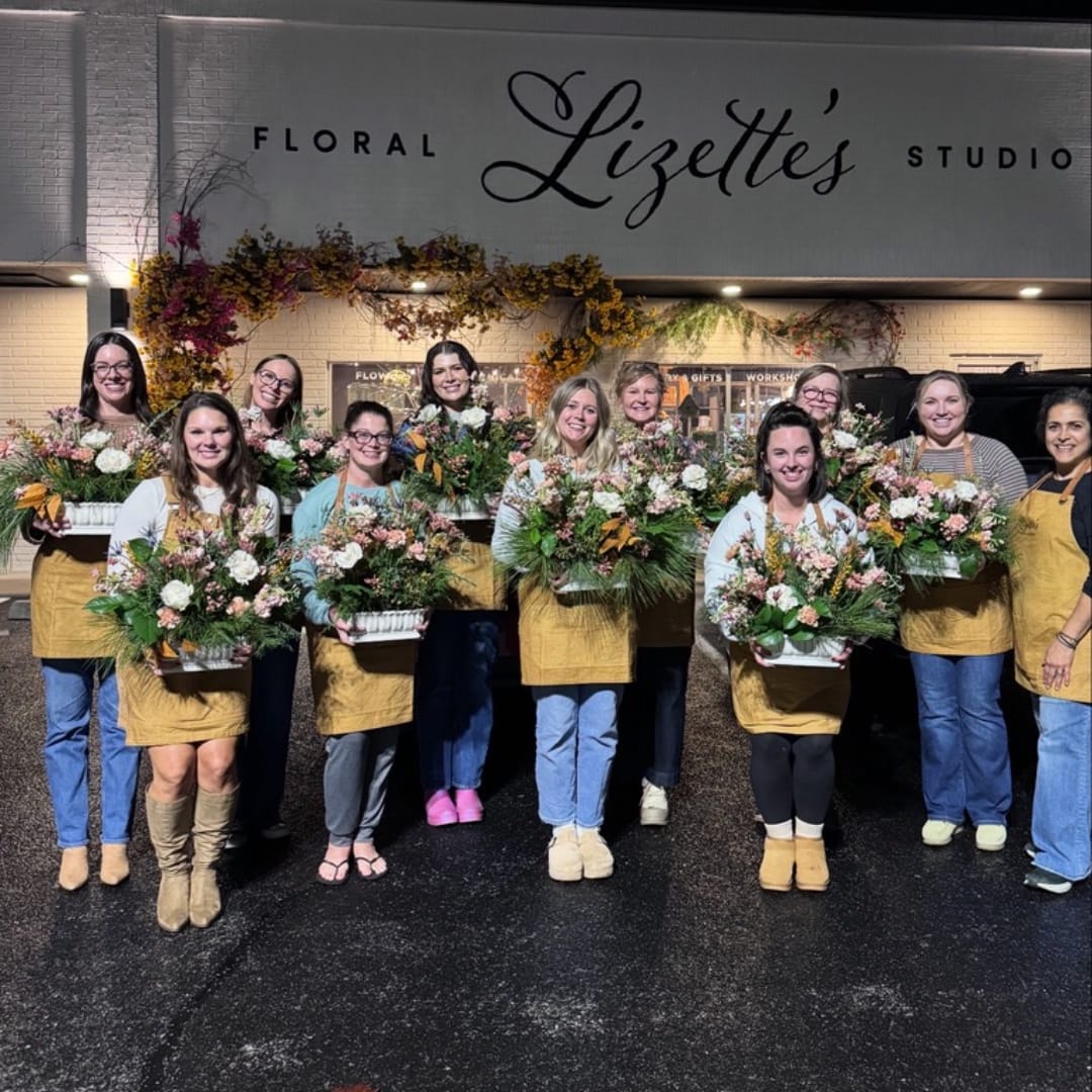 Group of florists holding mixed flower arrangements outside a floral studio