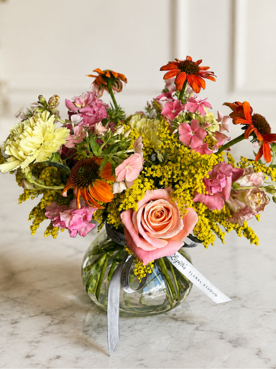 Mixed bouquet in a clear glass vase with pink, yellow, and orange flowers