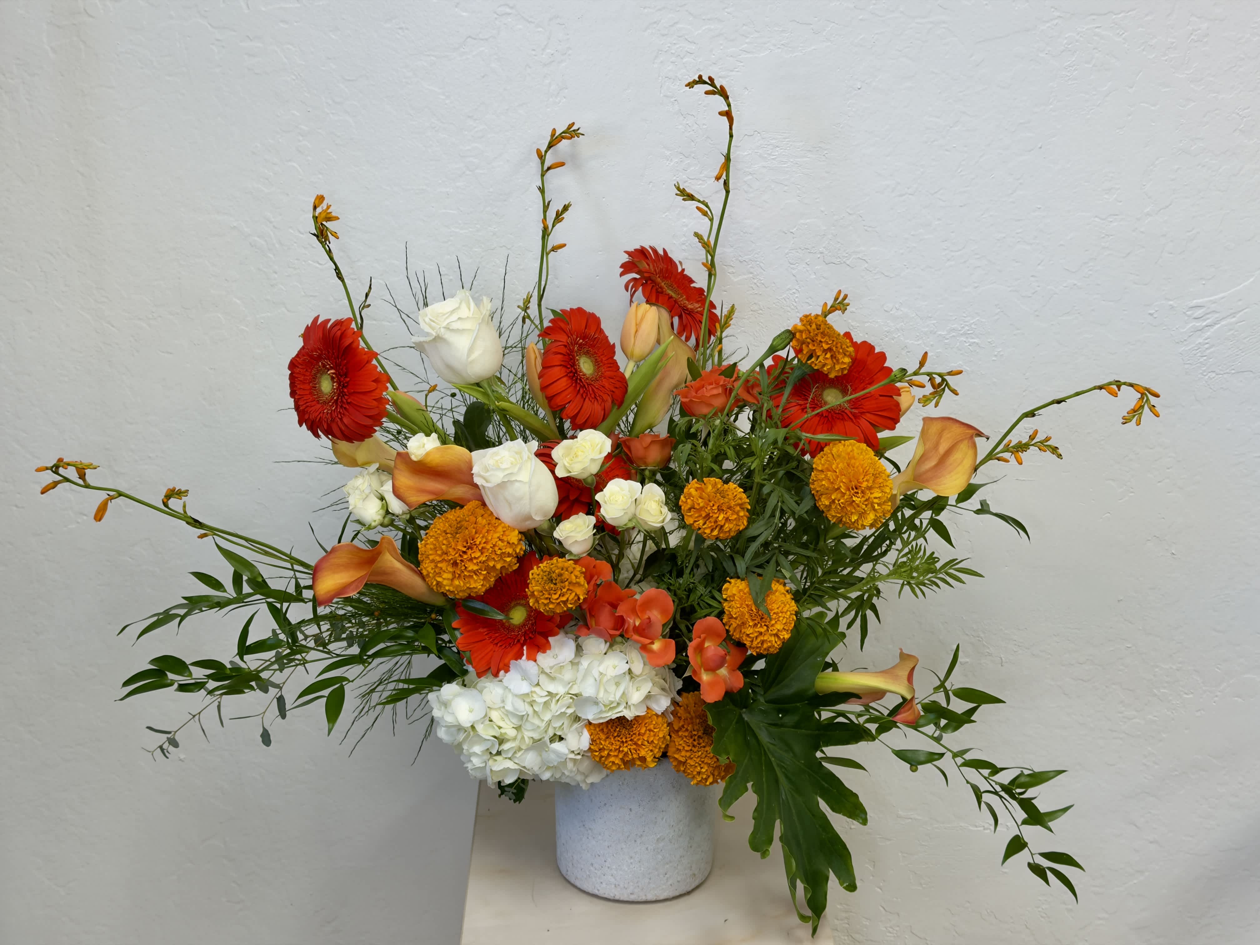 Bright mixed bouquet with gerbera daisies, roses, calla lilies, and hydrangea in a white vase