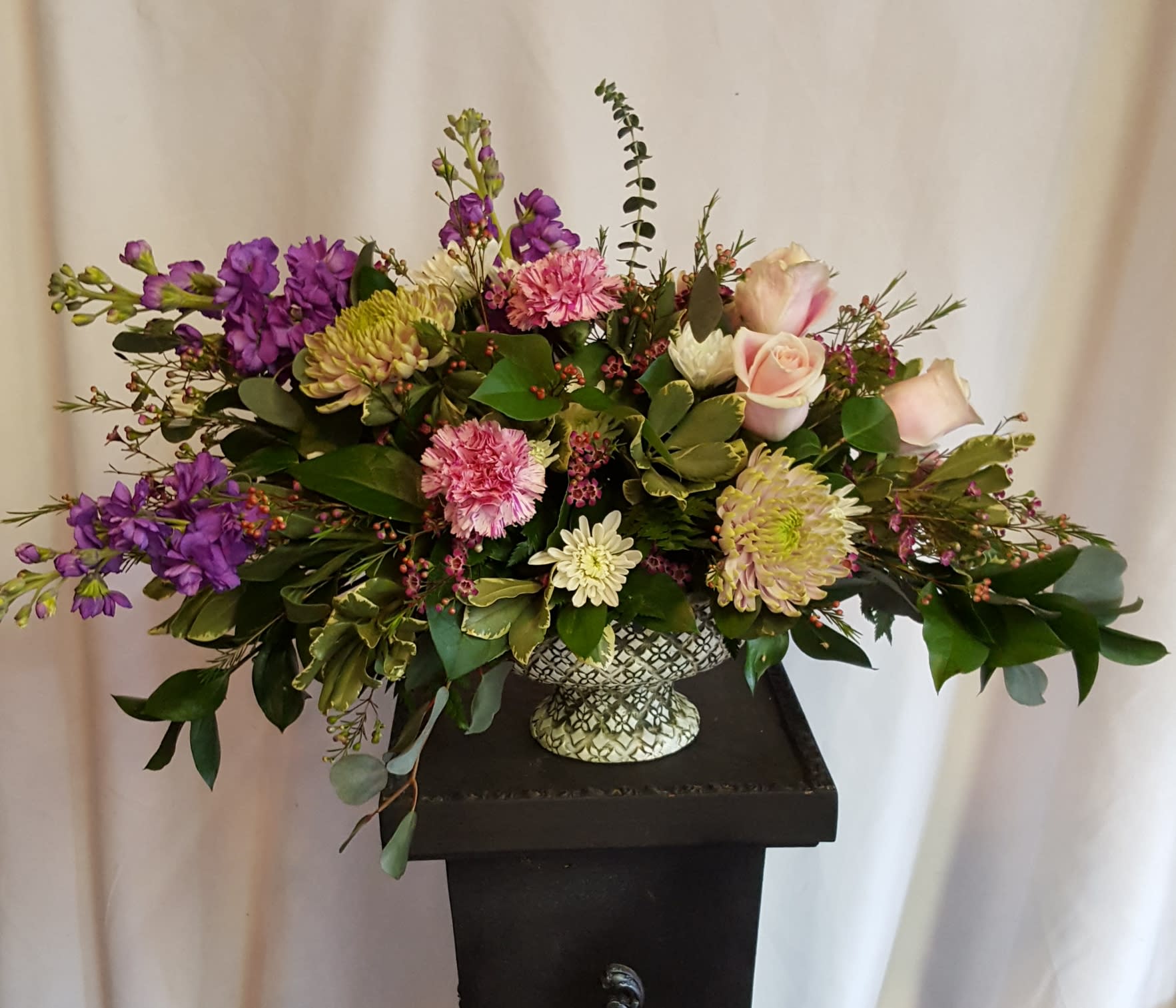 Mixed bouquet in a patterned vase with purple, pink, and cream flowers