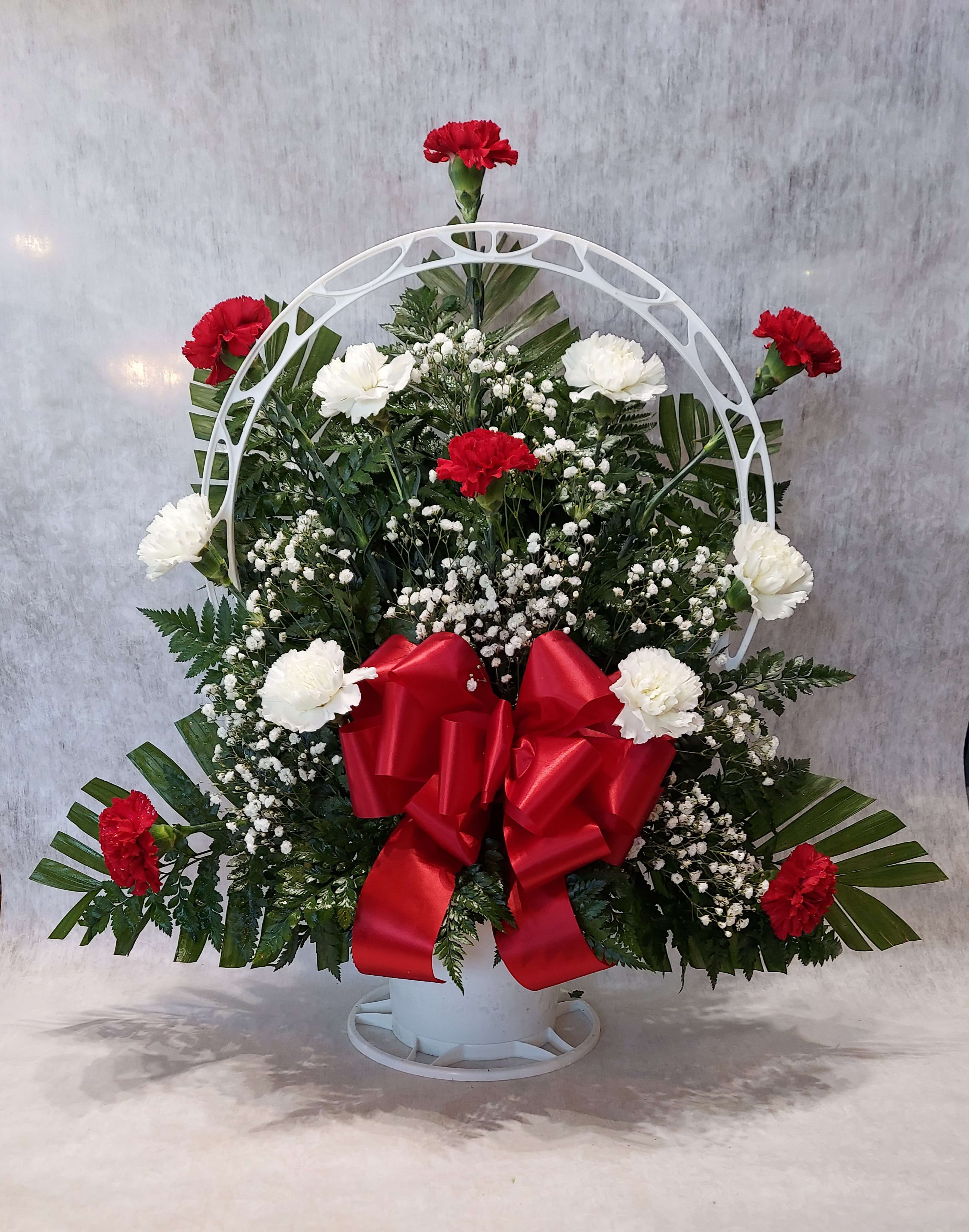 Standing floral wreath with red and white carnations and a red bow