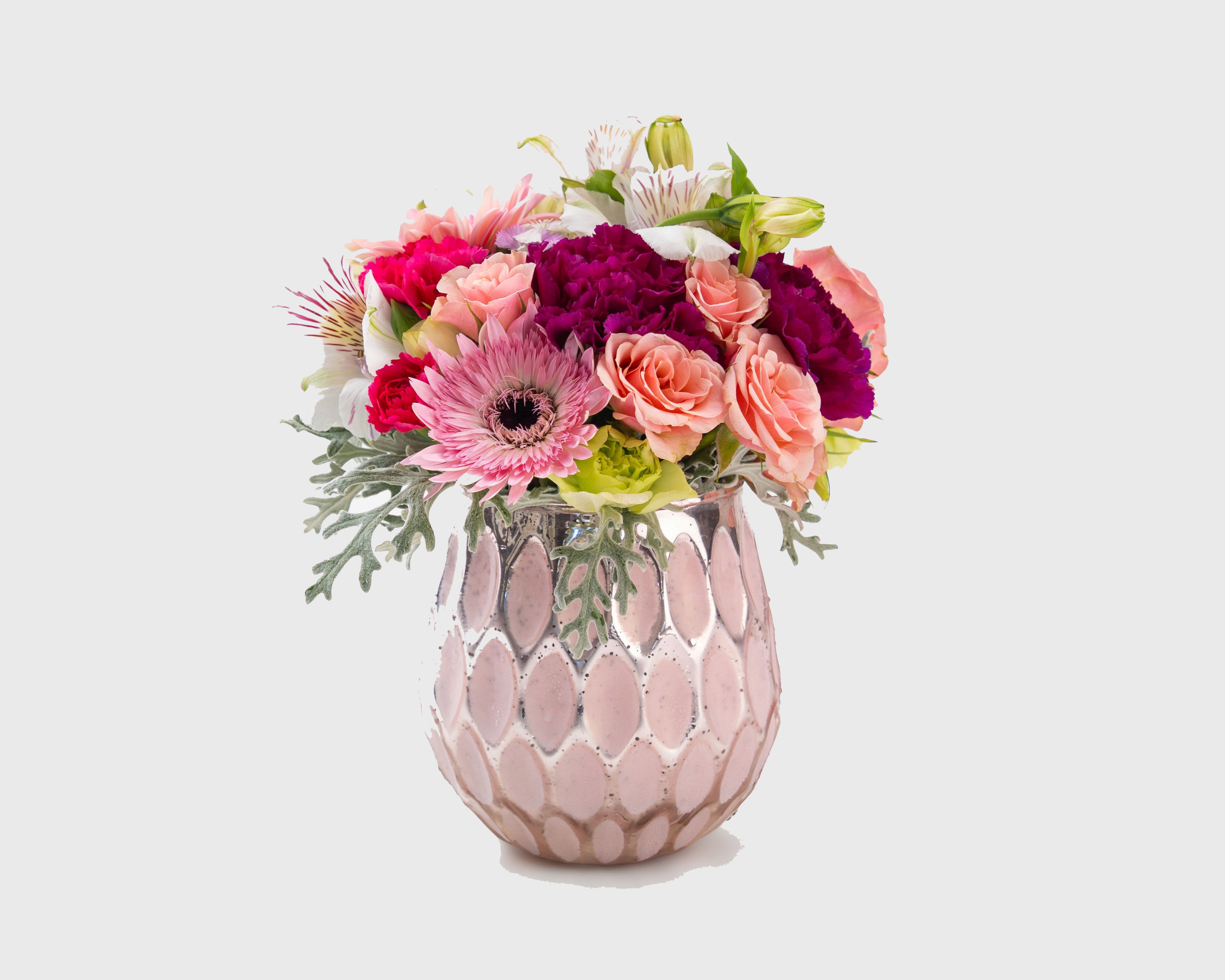 Mixed pink and peach flowers in a pink ceramic vase