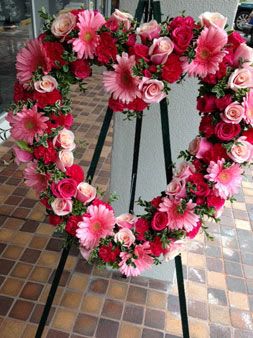Heart-shaped floral wreath with pink and red roses and daisies on an easel