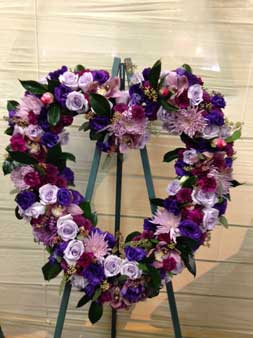 Heart-shaped floral wreath on an easel with purple and pink flowers