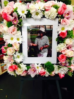 Flower wreath around a framed photo with pink roses and white daisies