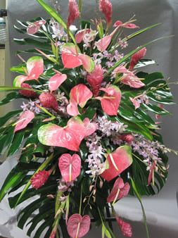 Pink anthuriums and small lilac flowers in a large standing arrangement
