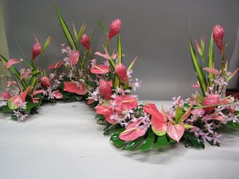 Pink floral garland with tall green leaves on a table