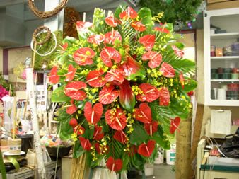 Large red anthurium arrangement with green foliage in a shop setting