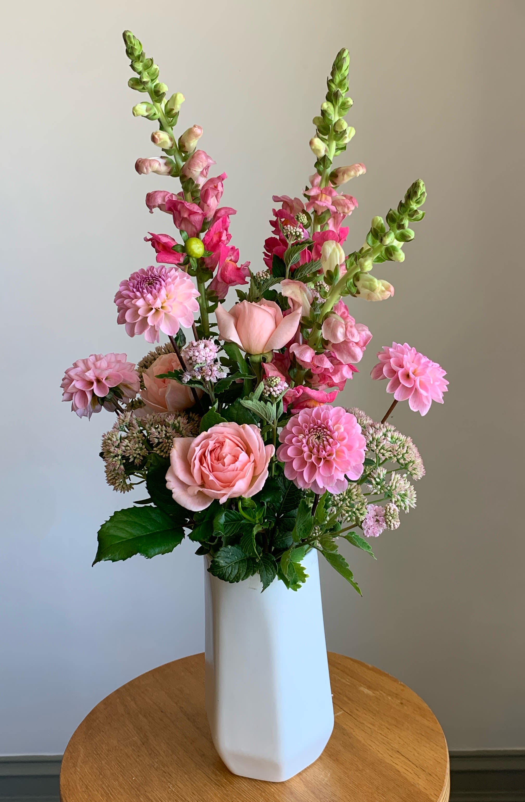 Pink and peach flowers arranged in a tall white vase