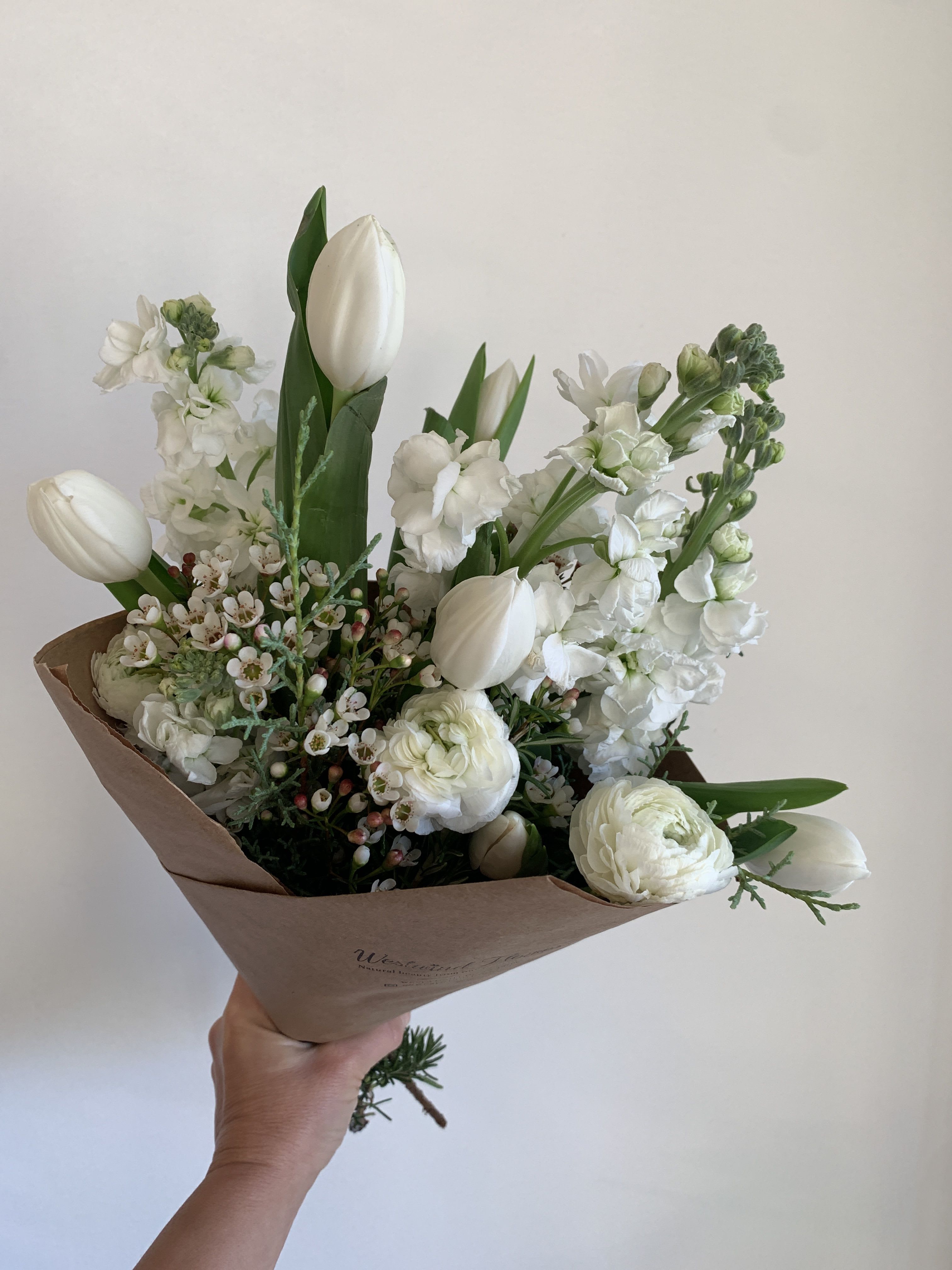 White tulips and ranunculus in brown paper wrapping