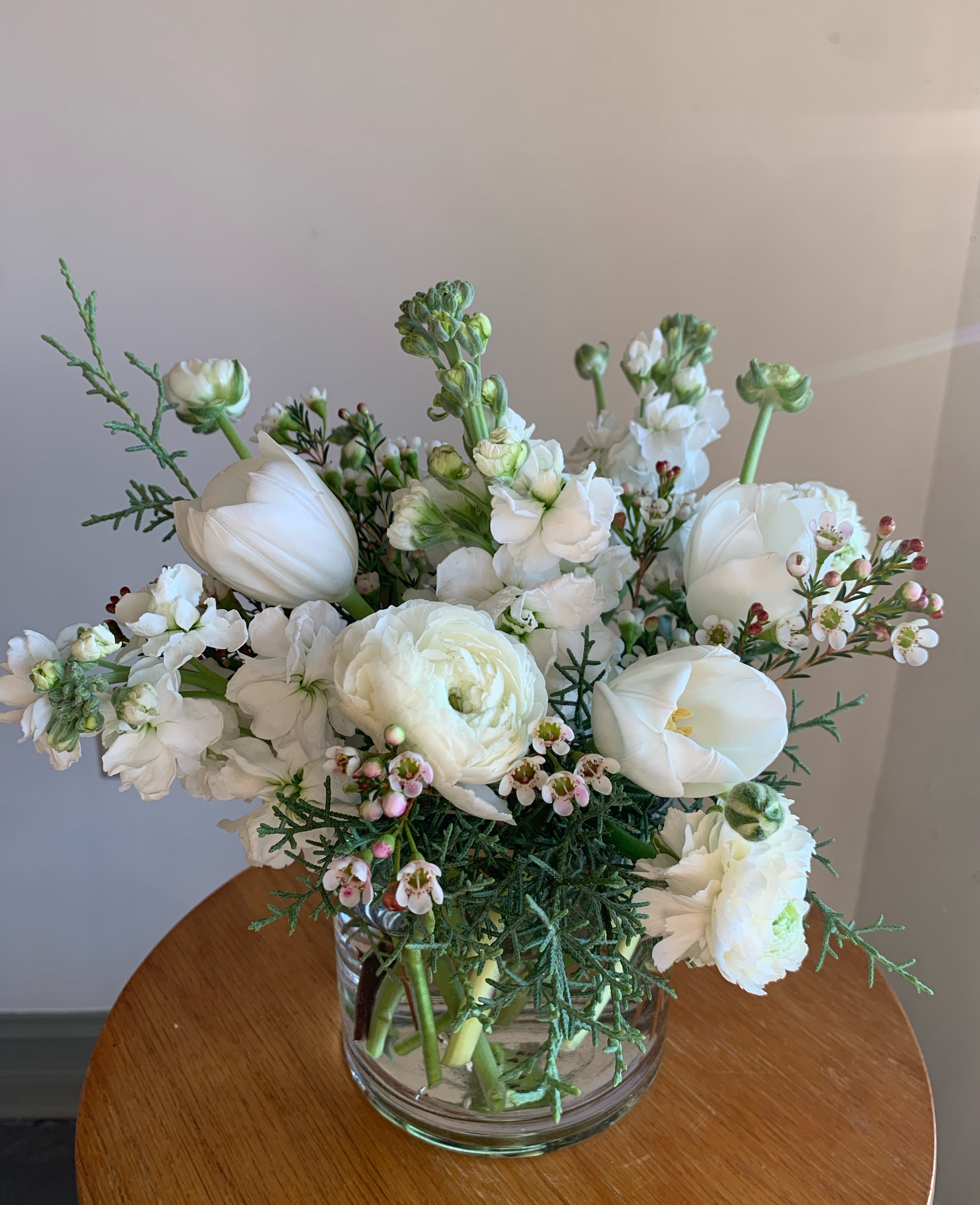White floral bouquet in a clear glass vase on a wooden table