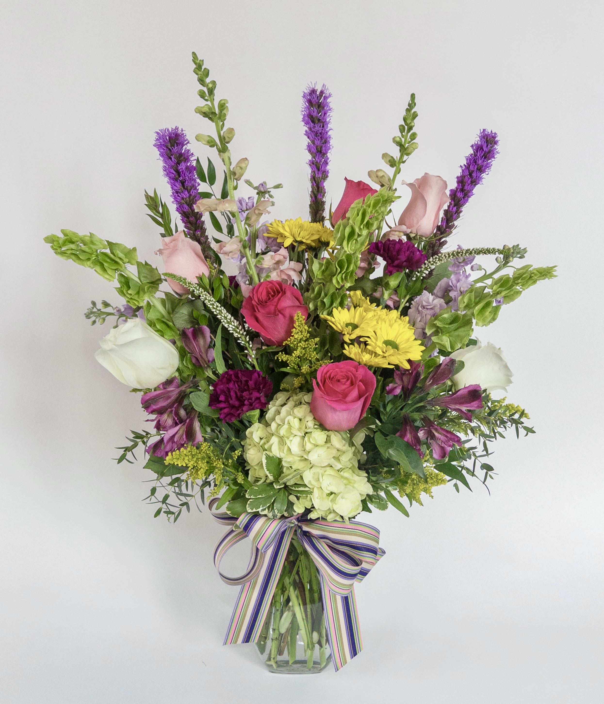 Mixed bouquet in a glass vase with pink, white, yellow, and purple flowers