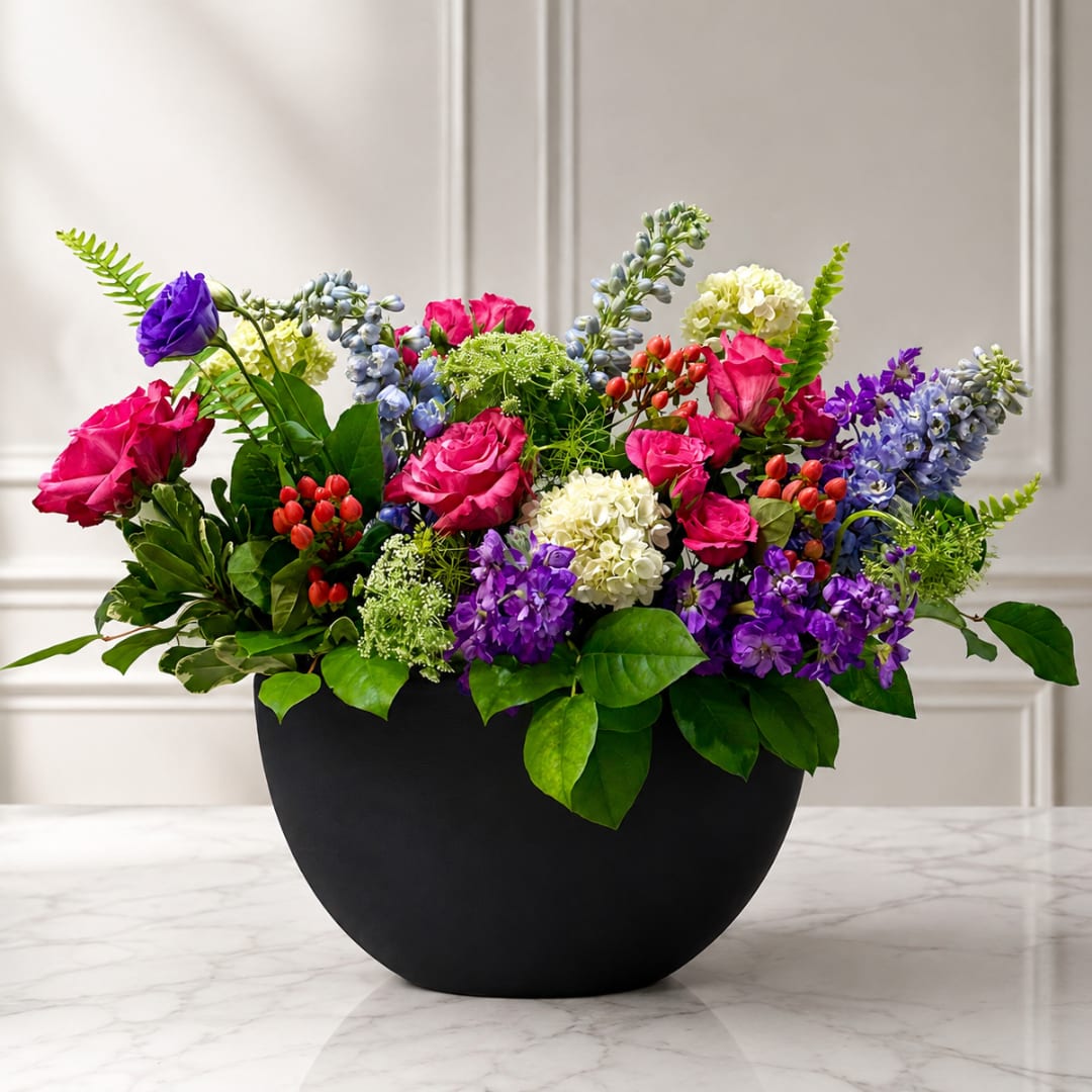 Colorful mixed flower arrangement in a black bowl vase