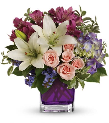Bouquet of white lilies, pink roses, and purple flowers in a purple vase
