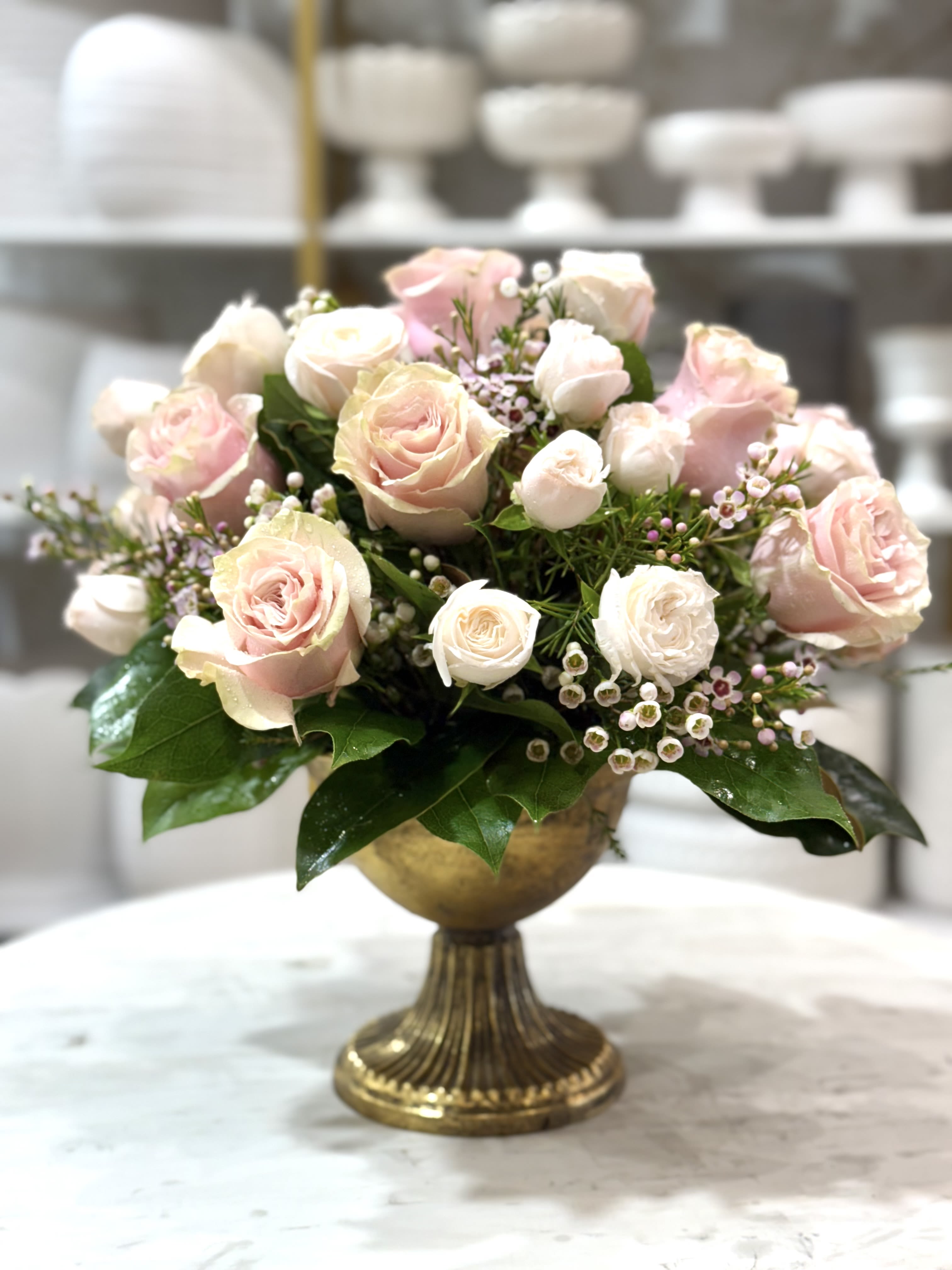 Pink and white roses arranged in a gold pedestal vase
