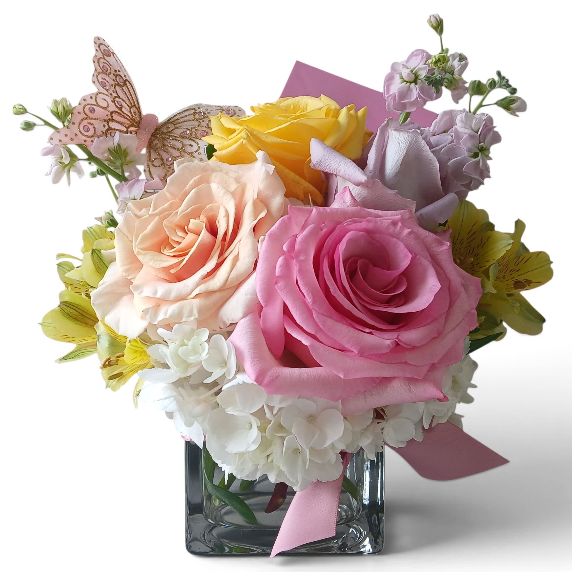 Bouquet of pink, peach, and yellow roses in a square glass vase