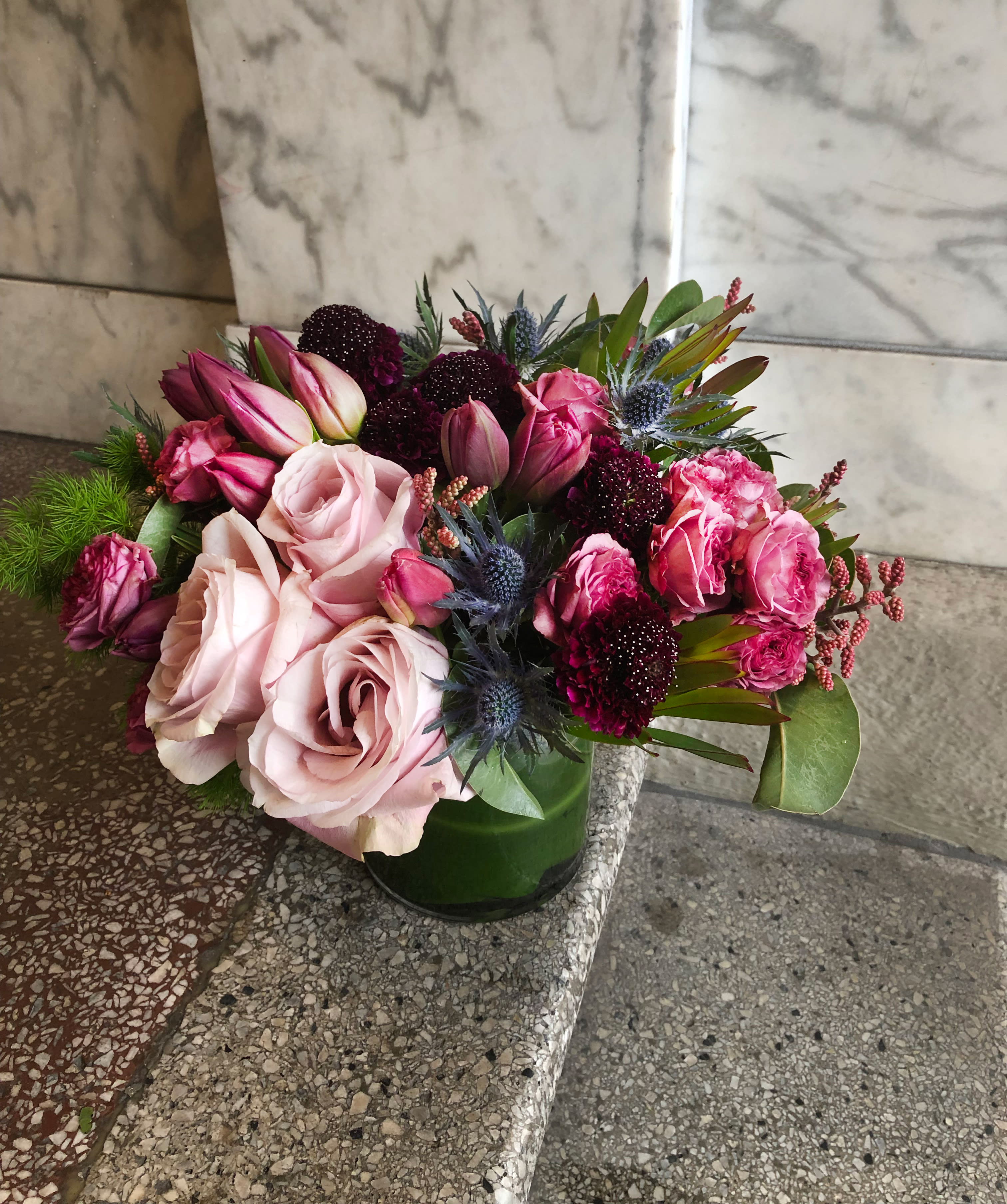 Moody Pinks - Yay for moody pinks!  Roses, Tulips, Scabiosa, and Thistle come together to create a love that's uniquely special. This is a great color combo to send to a person who loves jewel toned arrangements. We use the best flowers available in the palette that is available at the market.   NOTES: We will choose the freshest and most interesting ingredients at the market to make this arrangement shine. Vessels may be substituted depending on availability.   If any design element such as color or flower/foliage are very important to your order please contact us to ensure availability first by calling the shop at  415 751 2747  