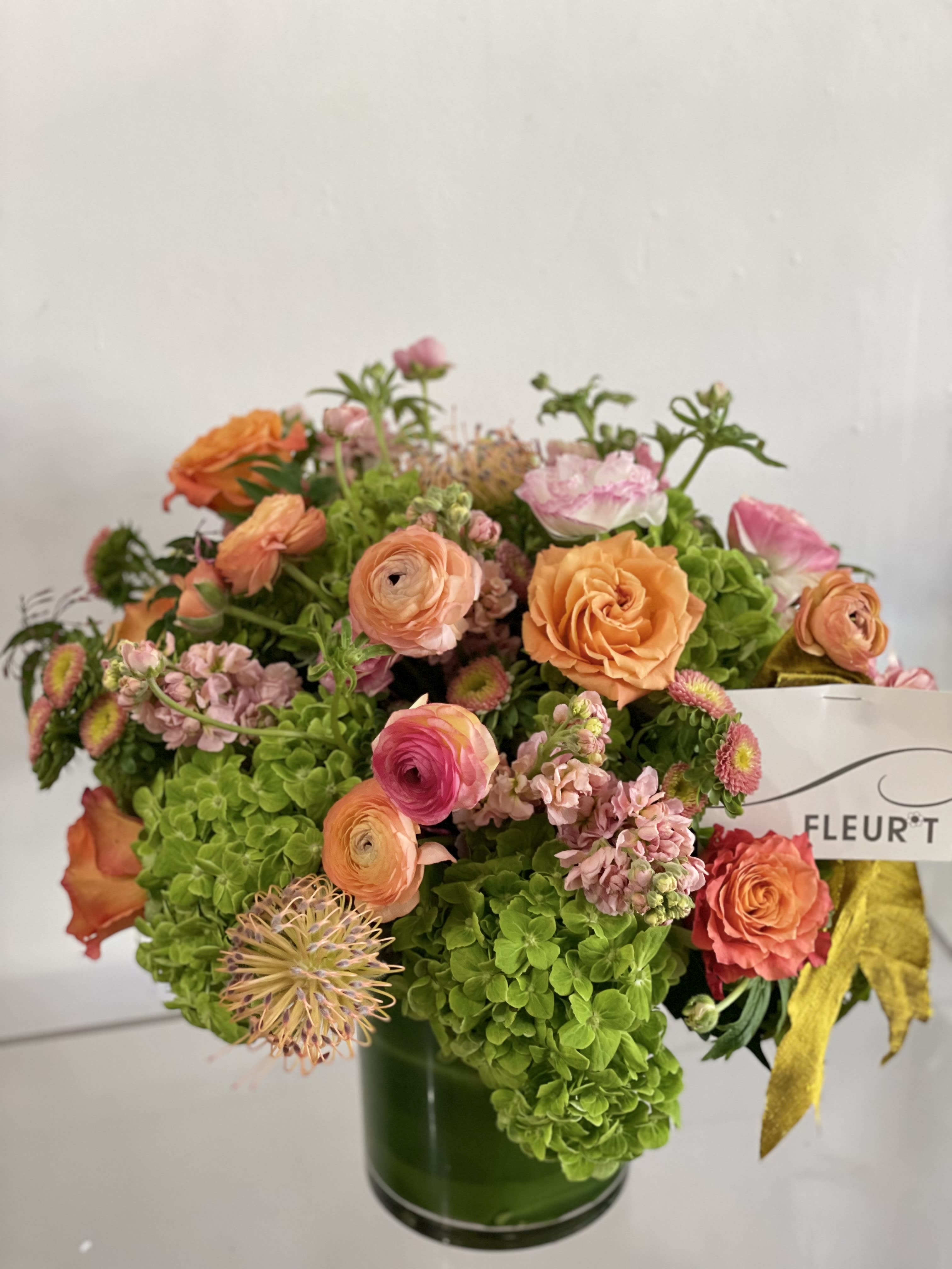 Bouquet of orange and pink flowers in a green glass vase