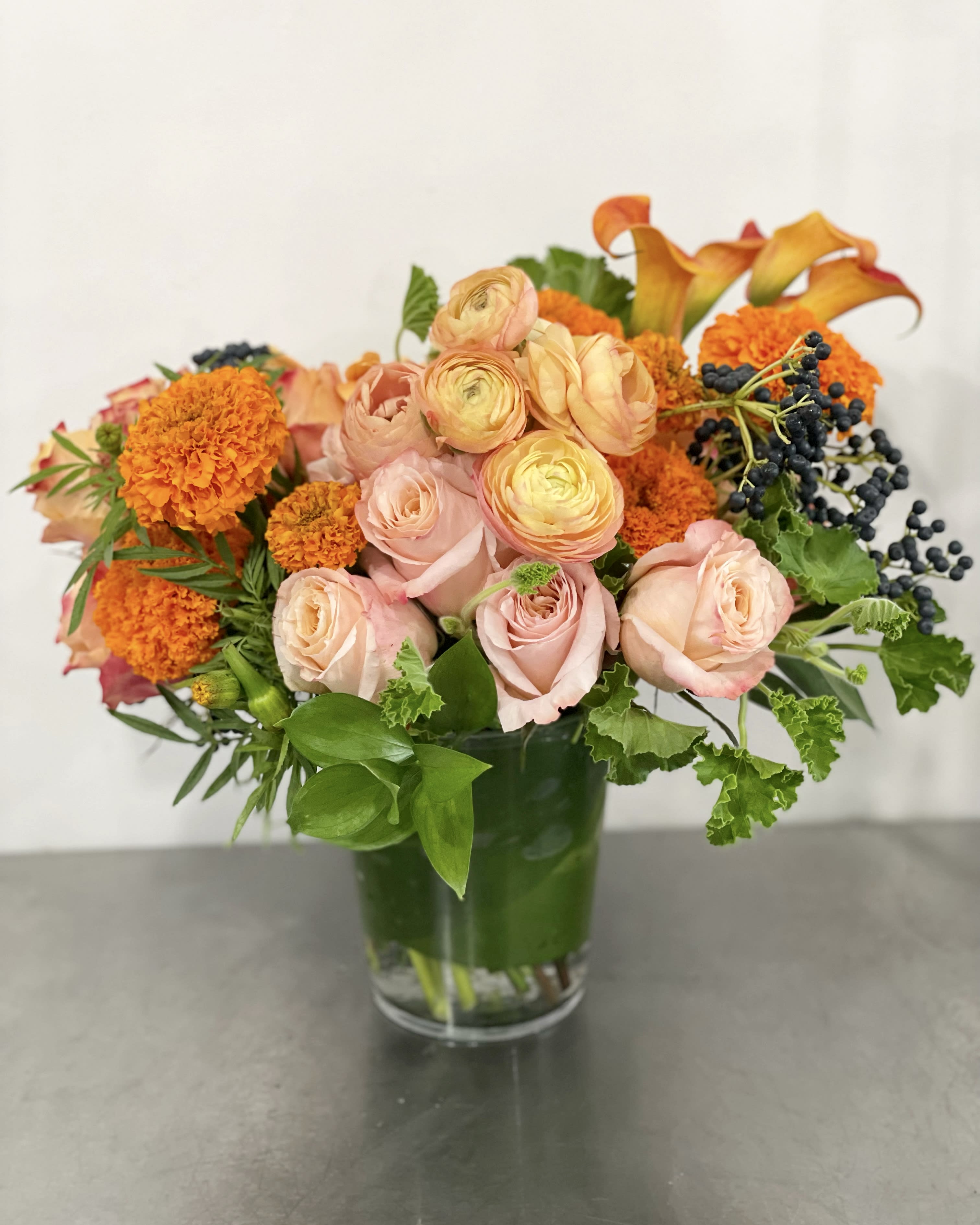 Orange Crush - Lovely arrangement of bright orange, peach and a pop of blue all designed into a ti leaf lined vase.  This two tone arrangement is a cheerful way to say Thank you or Happy Birthday!   If any design element such as color or flower/foliage are very important to your order please contact us to ensure availability first by calling the shop at  415 751 2747 or info @ fleurtstyle com  