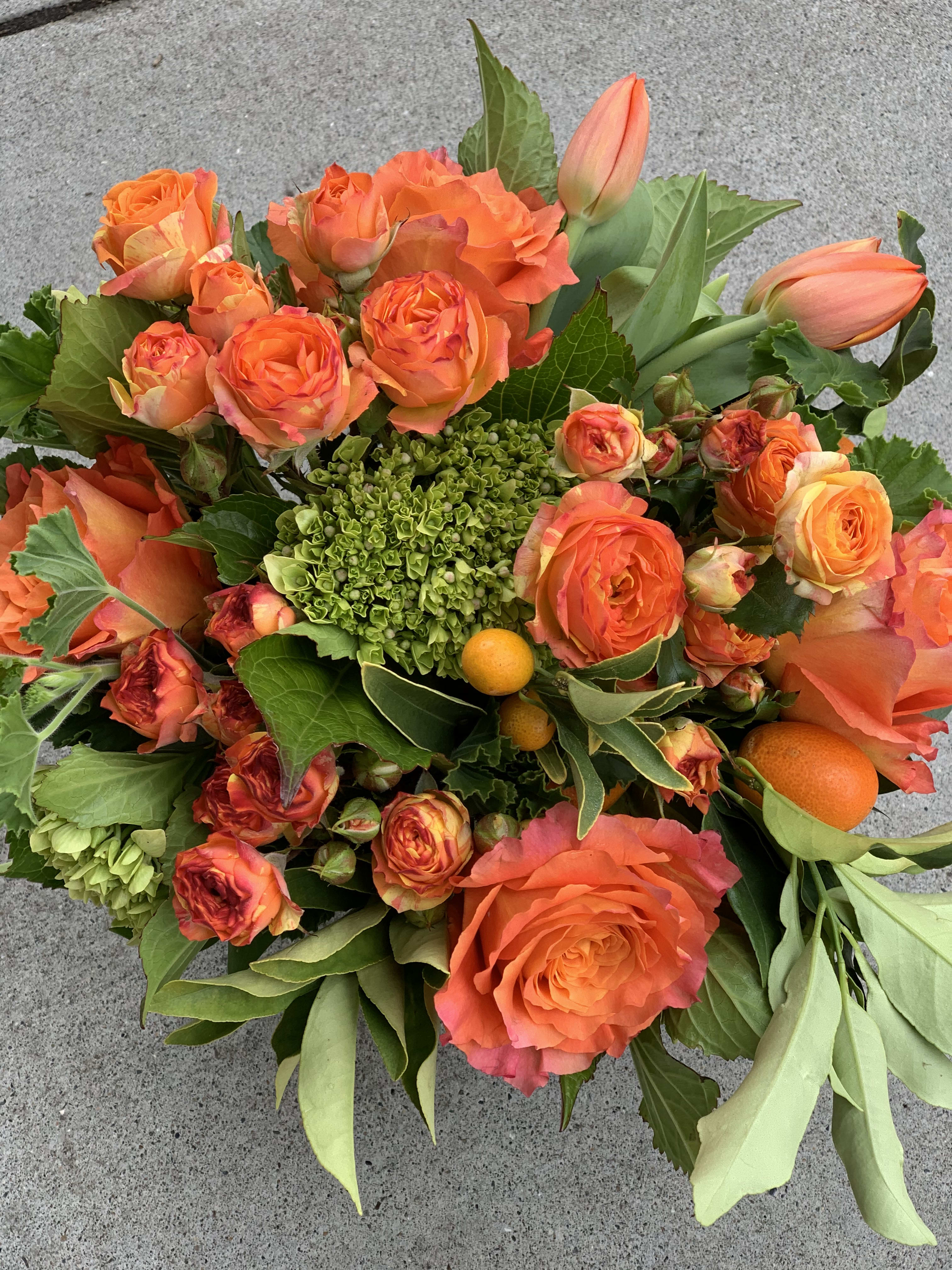 Sevilla Orange  - Monochromatic orange and green. This is a statement piece for the person who loves color.  The picture is meant to represent they style and color palette of what we will send out on your behalf.   Standard- Side table, desk, vanity, Standard small.  Deluxe-(PICTURED)  Dinner table, coffee table   Premium- Premium blooms added and it will have the largest footprint suitable for a large coffee table, entry way, or credenza   NOTES: We will choose the freshest and most interesting ingredients at the market to make this arrangement shine. Vessels may be substituted depending on availability.   If any design element such as color or flower/foliage are very important to your order please contact us to ensure availability first by calling the shop at  415 751 2747  