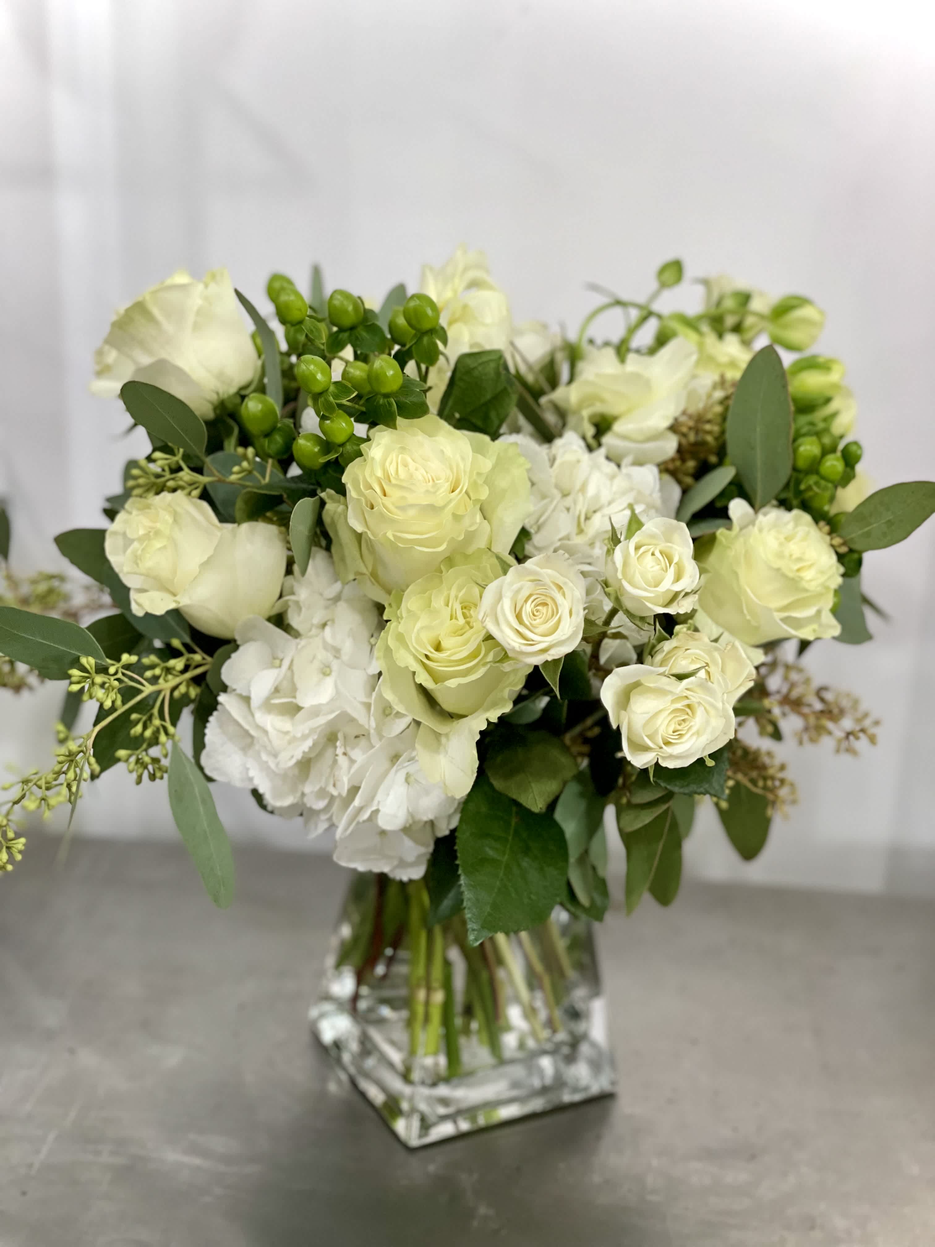 White roses and hydrangeas in a clear glass vase