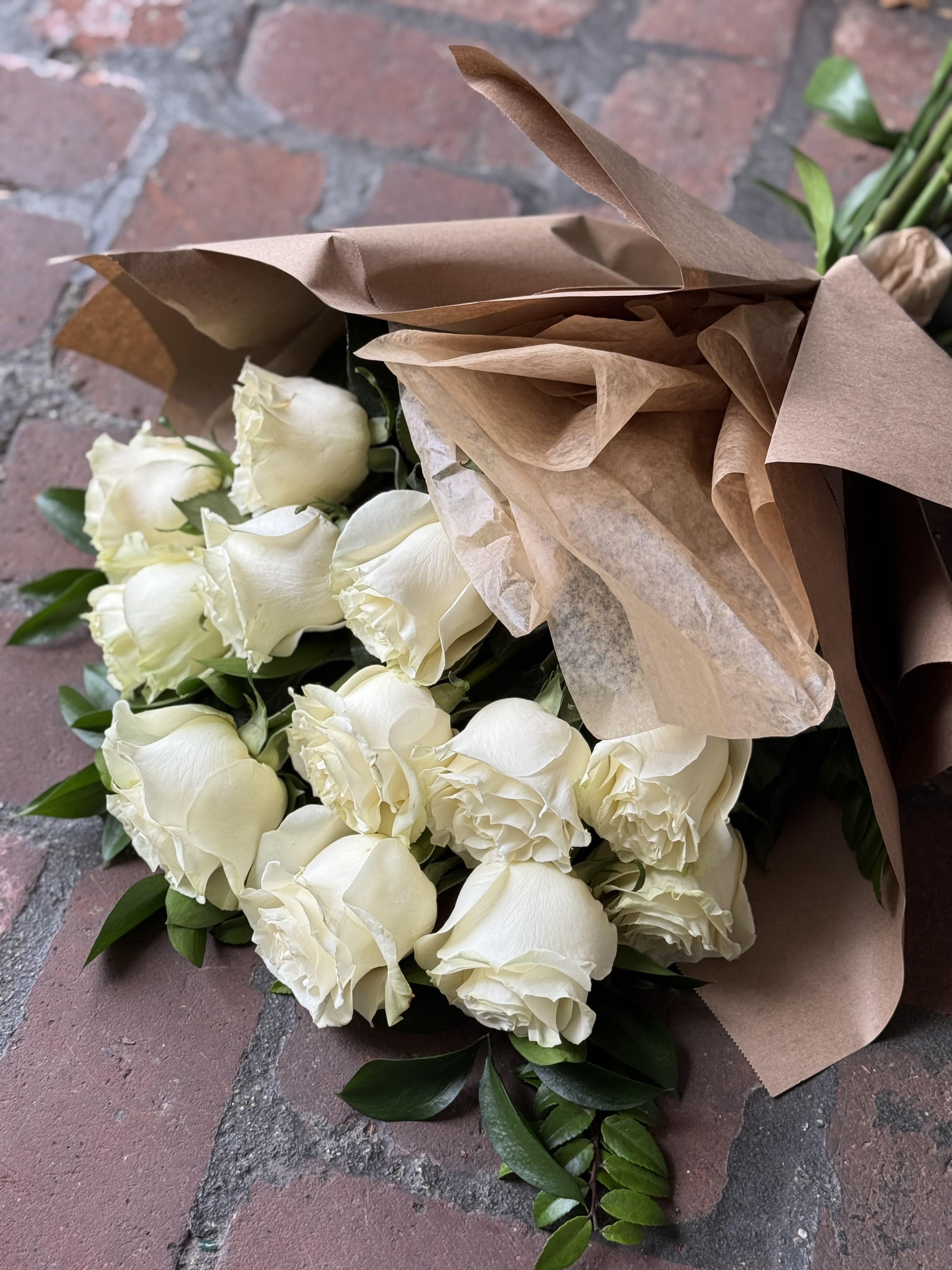 Bouquet of white roses wrapped in brown paper