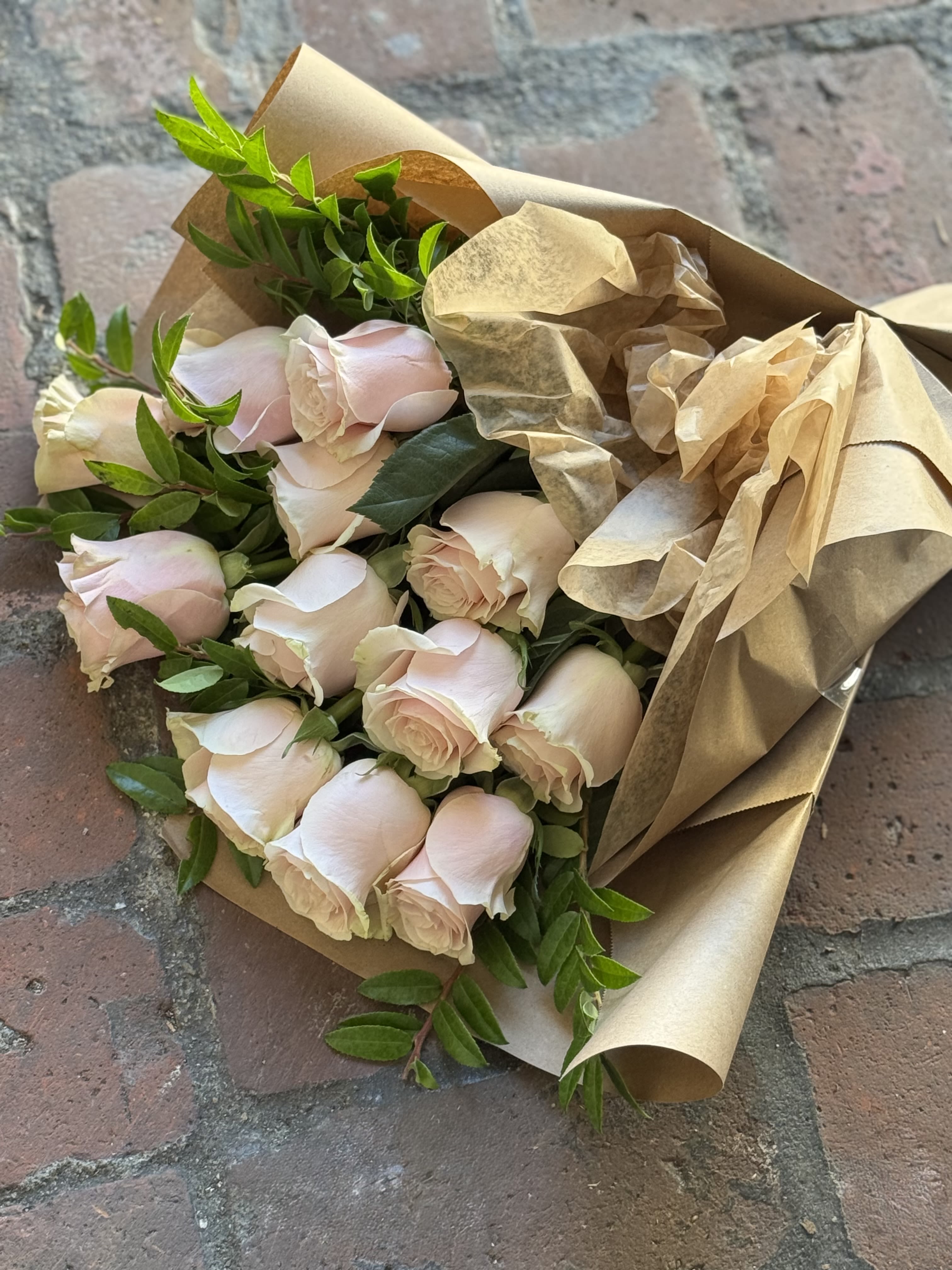Bouquet of pale pink roses wrapped in brown paper