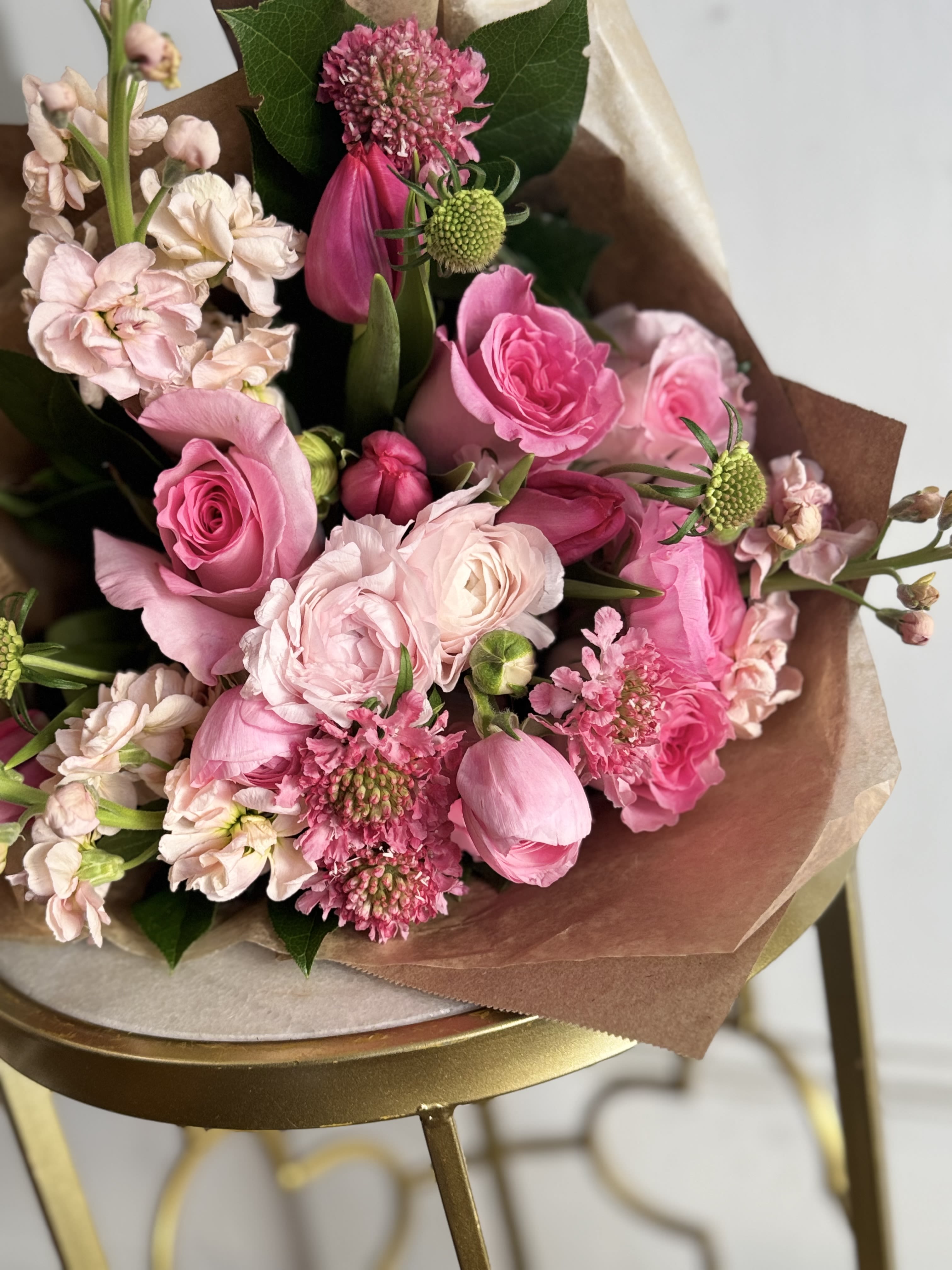 Pink mixed bouquet with roses and tulip buds wrapped in brown paper