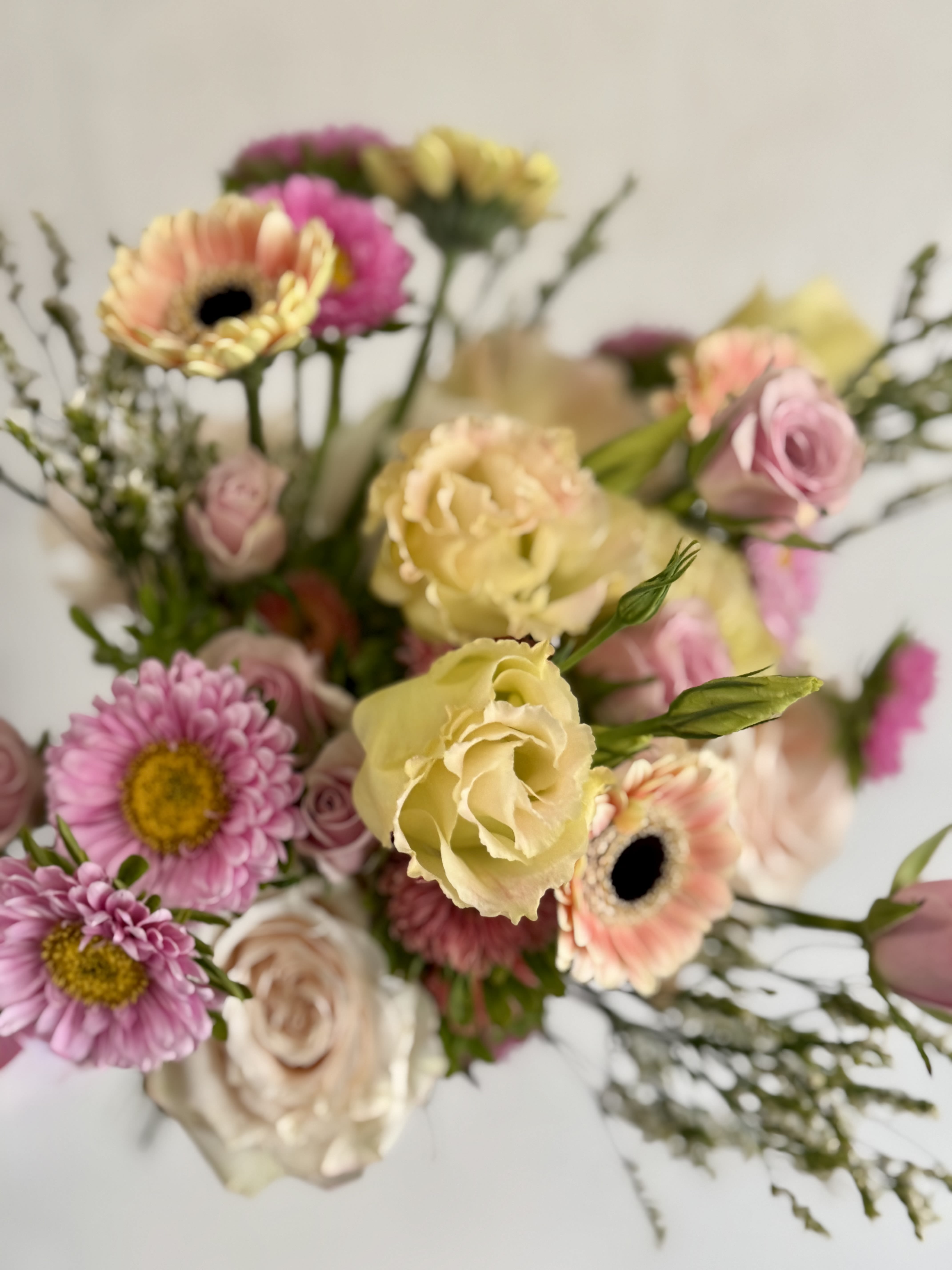 Petite Pink Butter  - The hand-tied composition reads airy and effortless-buttery yellow and peach accents lift the palette so it feels cheerful without being overpowering, perfect for birthdays, thank-you gifts, or a light celebration.The loose, natural styling lets each stem breathe, creating movement and a garden-fresh look in pink, yellow, white, and peach tones.  This petite bouquet is ideal for sending to a mom, close friend, or colleague when you want to brighten someone's day with a gentle, romantic touch. Its smaller scale works well for delivery to a home or office-order with confidence knowing it's designed to look freshly gathered and easy to care for with fresh water and a trim to stems every few days.