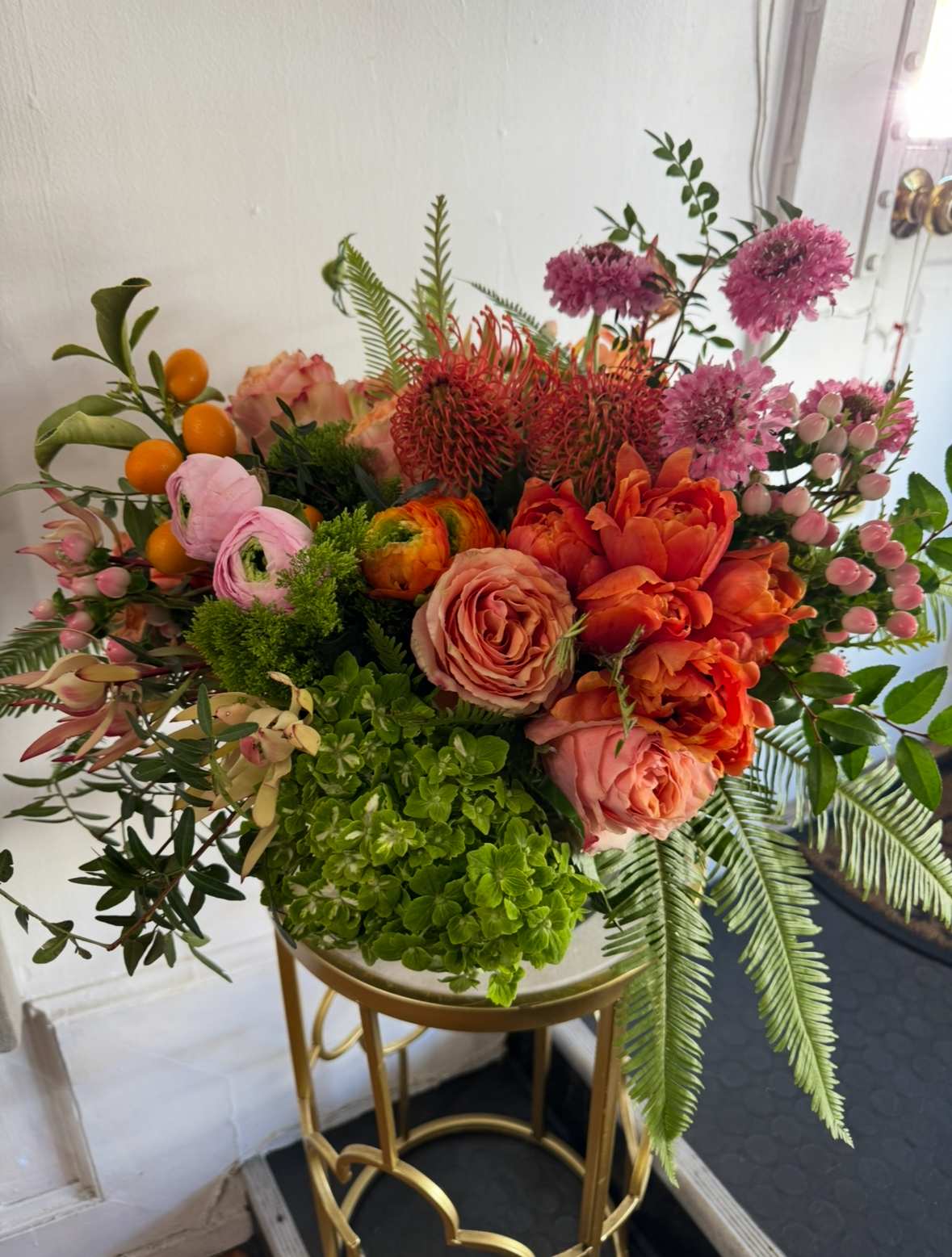 Mixed bouquet with orange and pink flowers in a gold stand