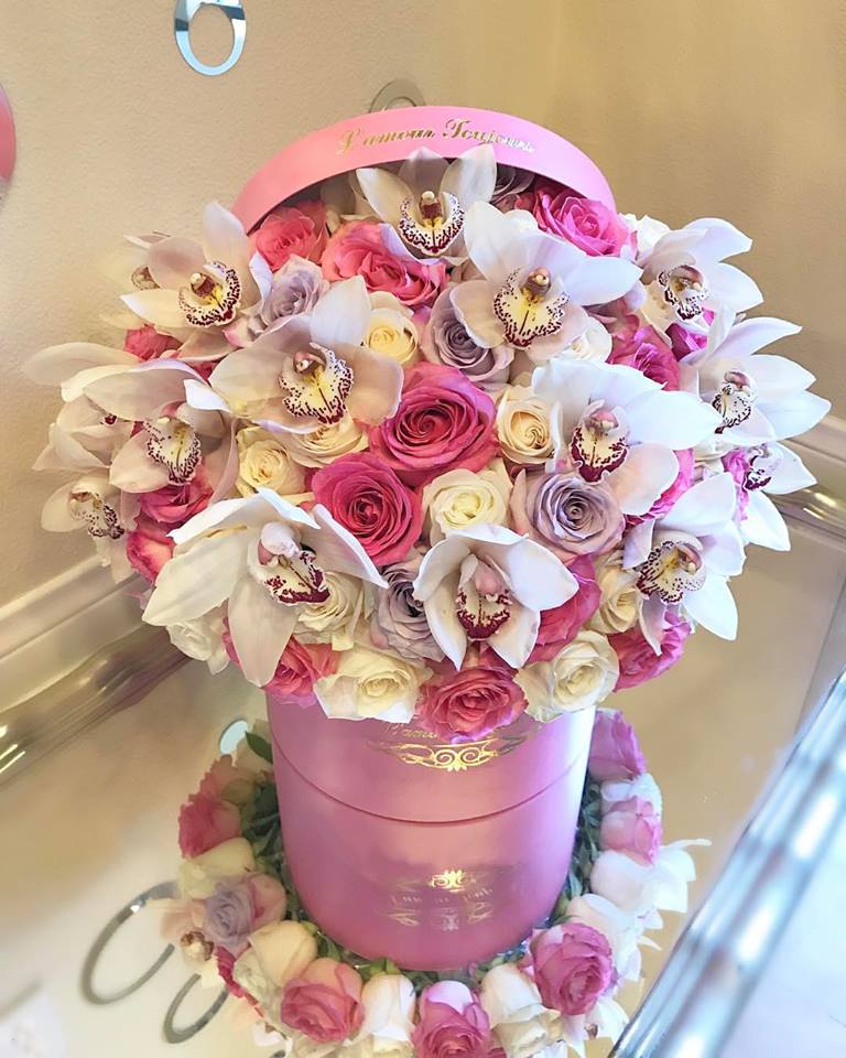 Pink and white roses with white orchids in a pink hatbox