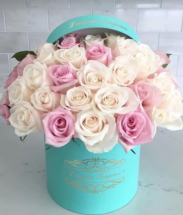 Pink and white roses arranged in a turquoise hat box