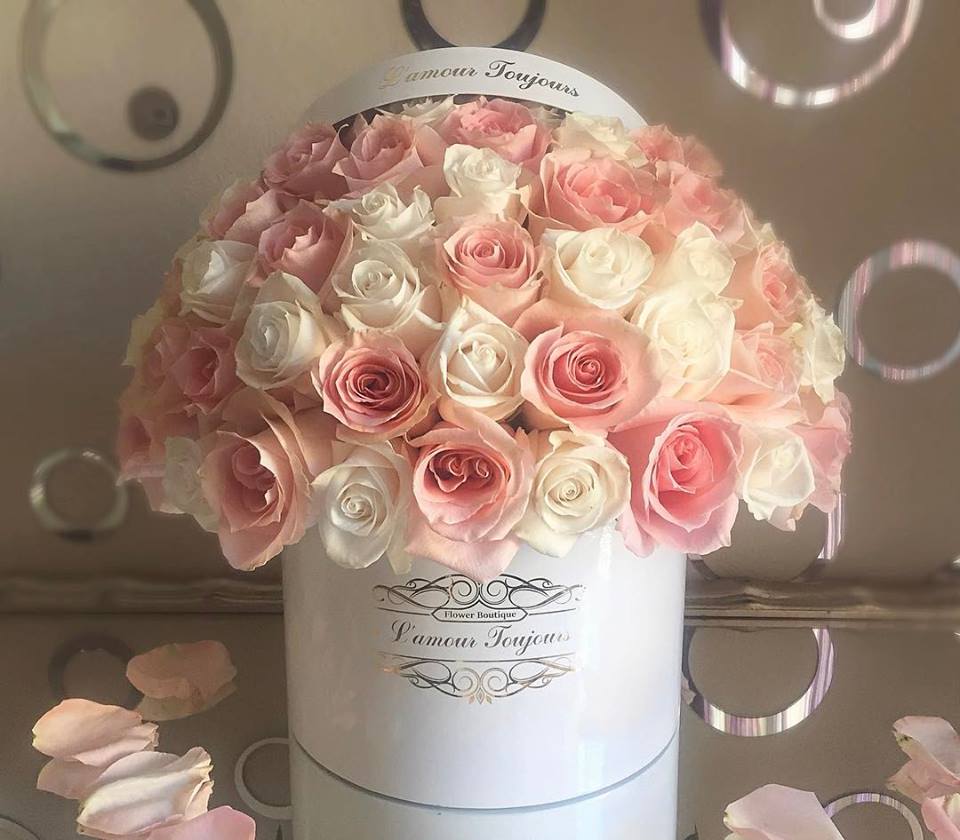 Pink and white roses arranged in a round white hat box