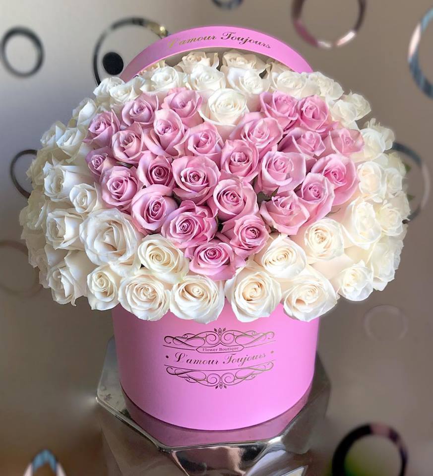Round pink hatbox filled with tightly packed pink and white roses
