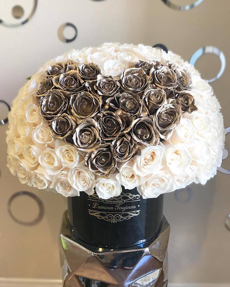 Heart-shaped rose arrangement in a black hatbox on a mirrored stand