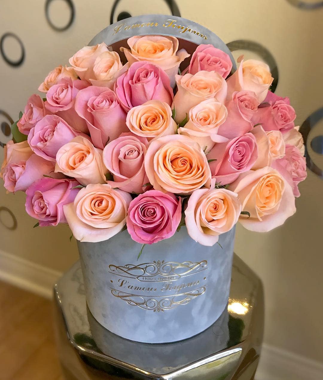 Round hat box of pink and peach roses arranged tightly together