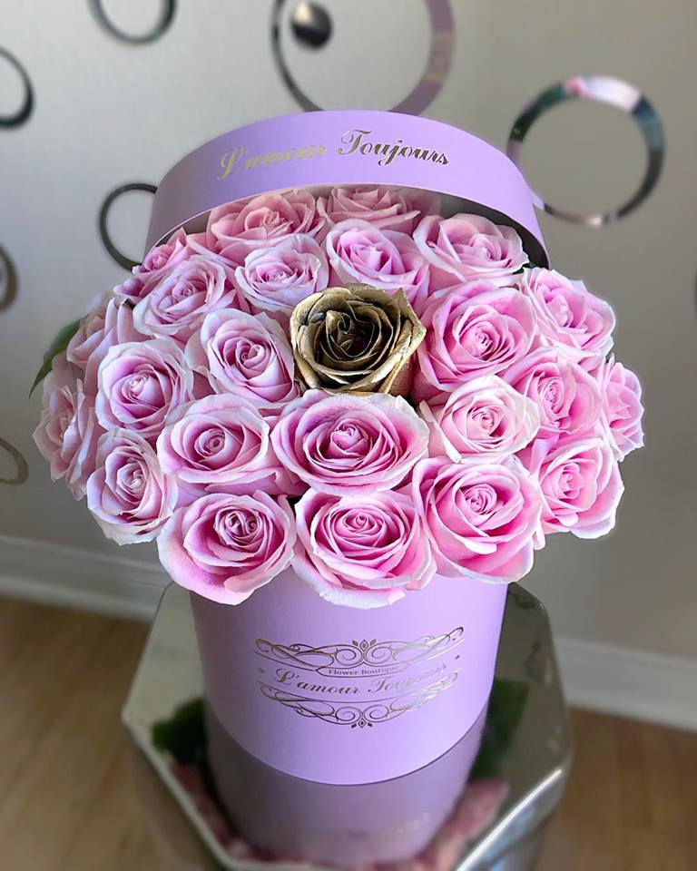 Round hatbox of light pink roses with a single gold rose in a lavender cylinder box
