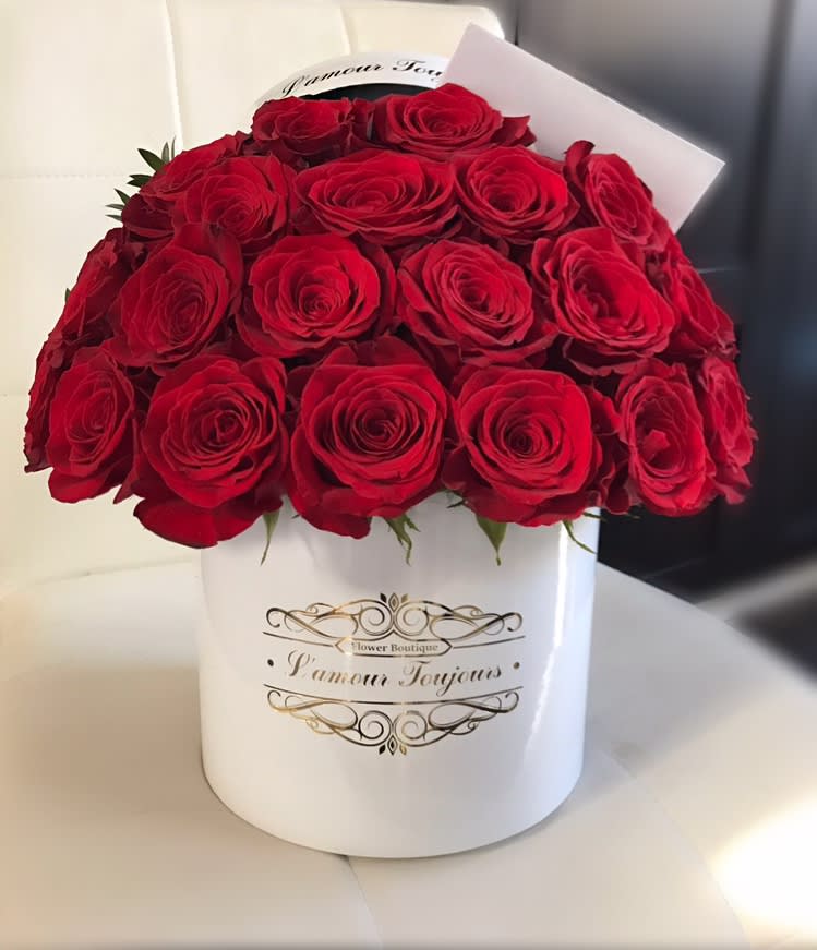 Round white hatbox of red roses with a small card on a white seat