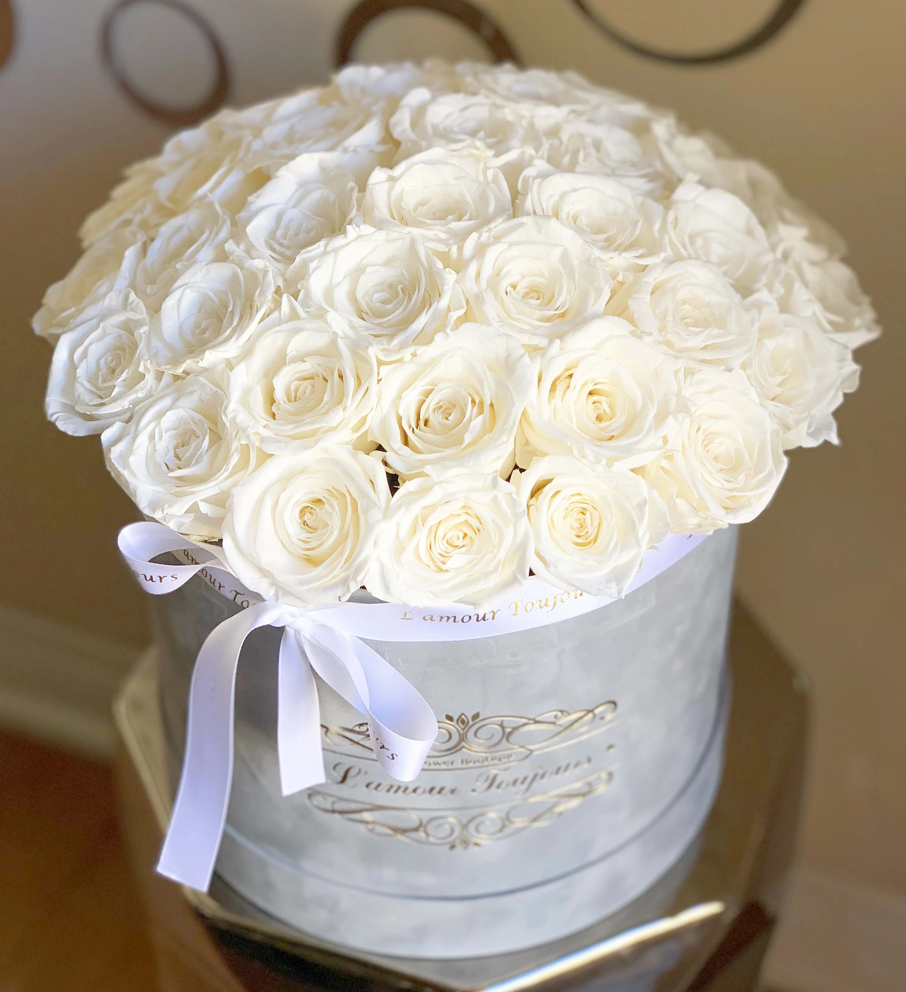 Round bouquet of white roses in a white hatbox with a ribbon