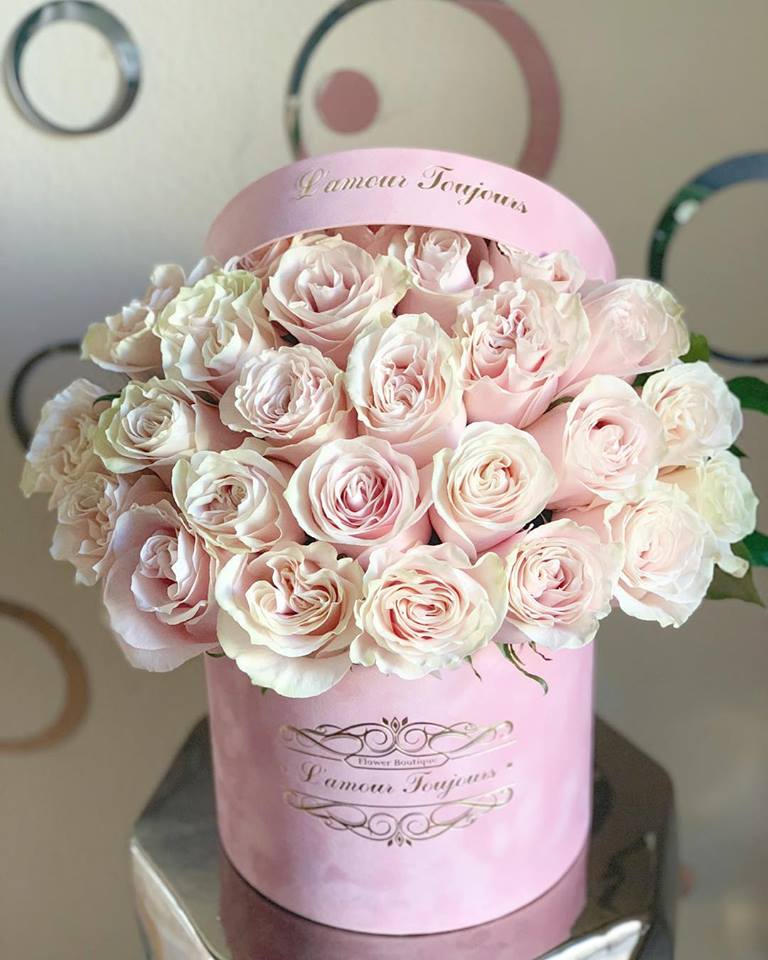 Round pink hat box filled with pale pink roses